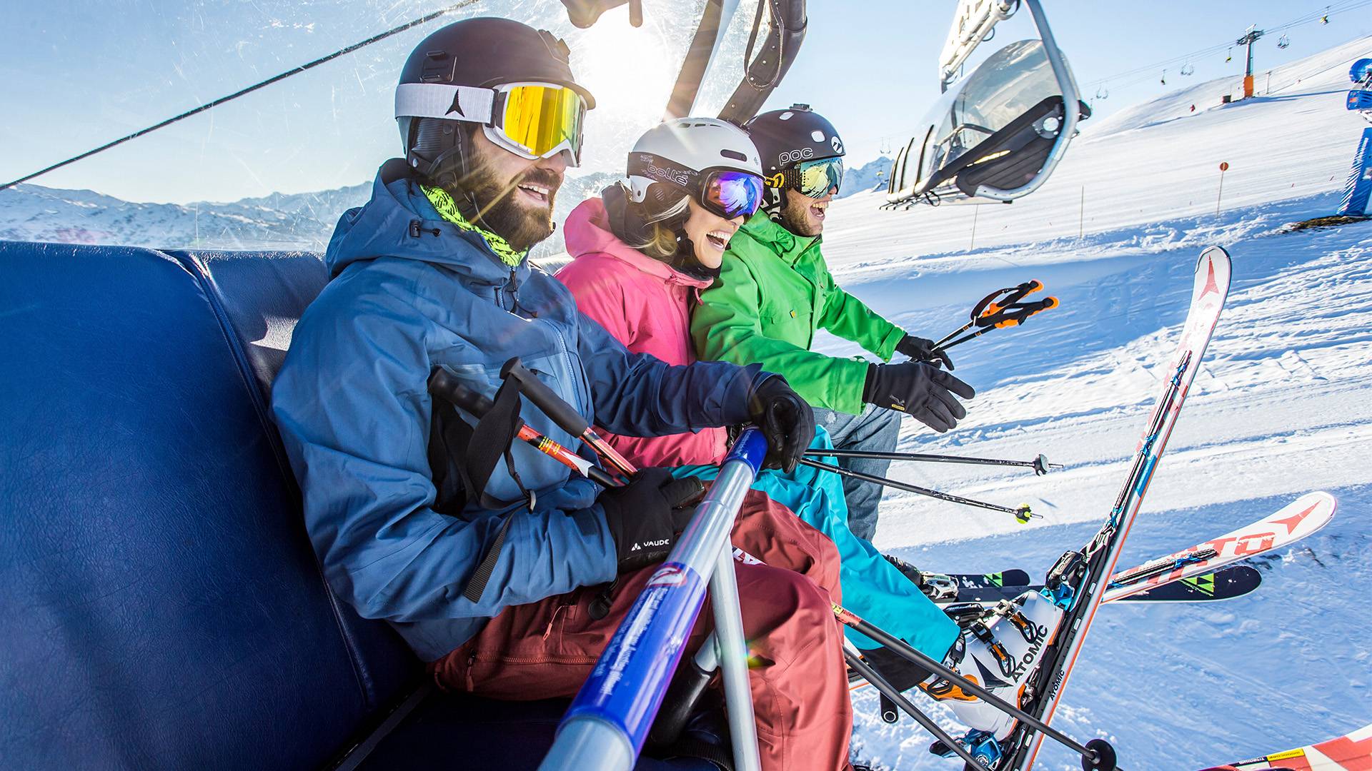 Lachende skiërs rijden op de stoeltjeslift.
