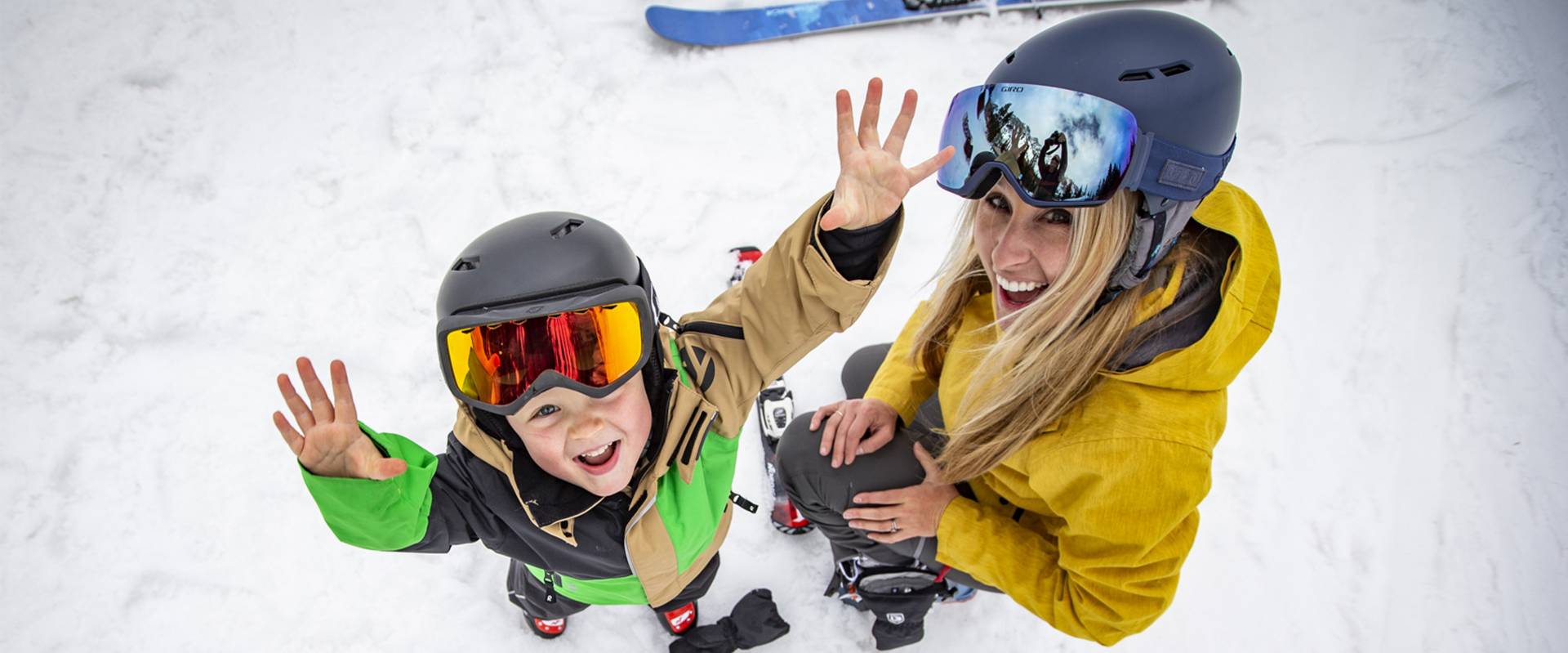A mother is helping her child put on their skiing equipment.