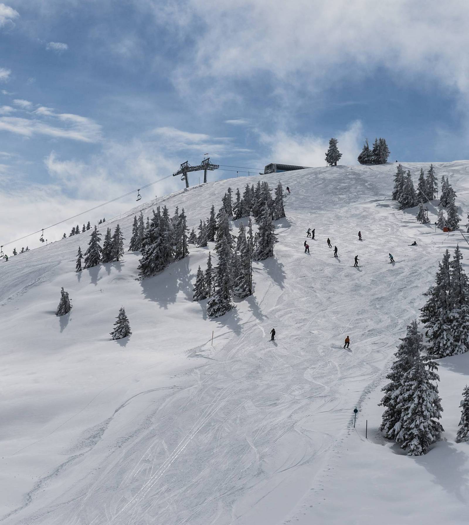 Aufnahme eines Berges mit Skipiste und Skifahrern.