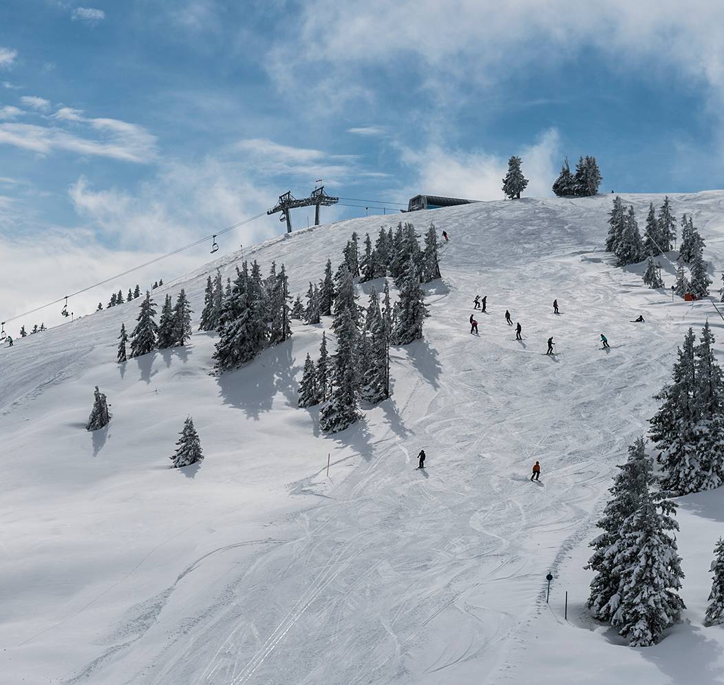 Aufnahme eines Berges mit Skipiste und Skifahrern.
