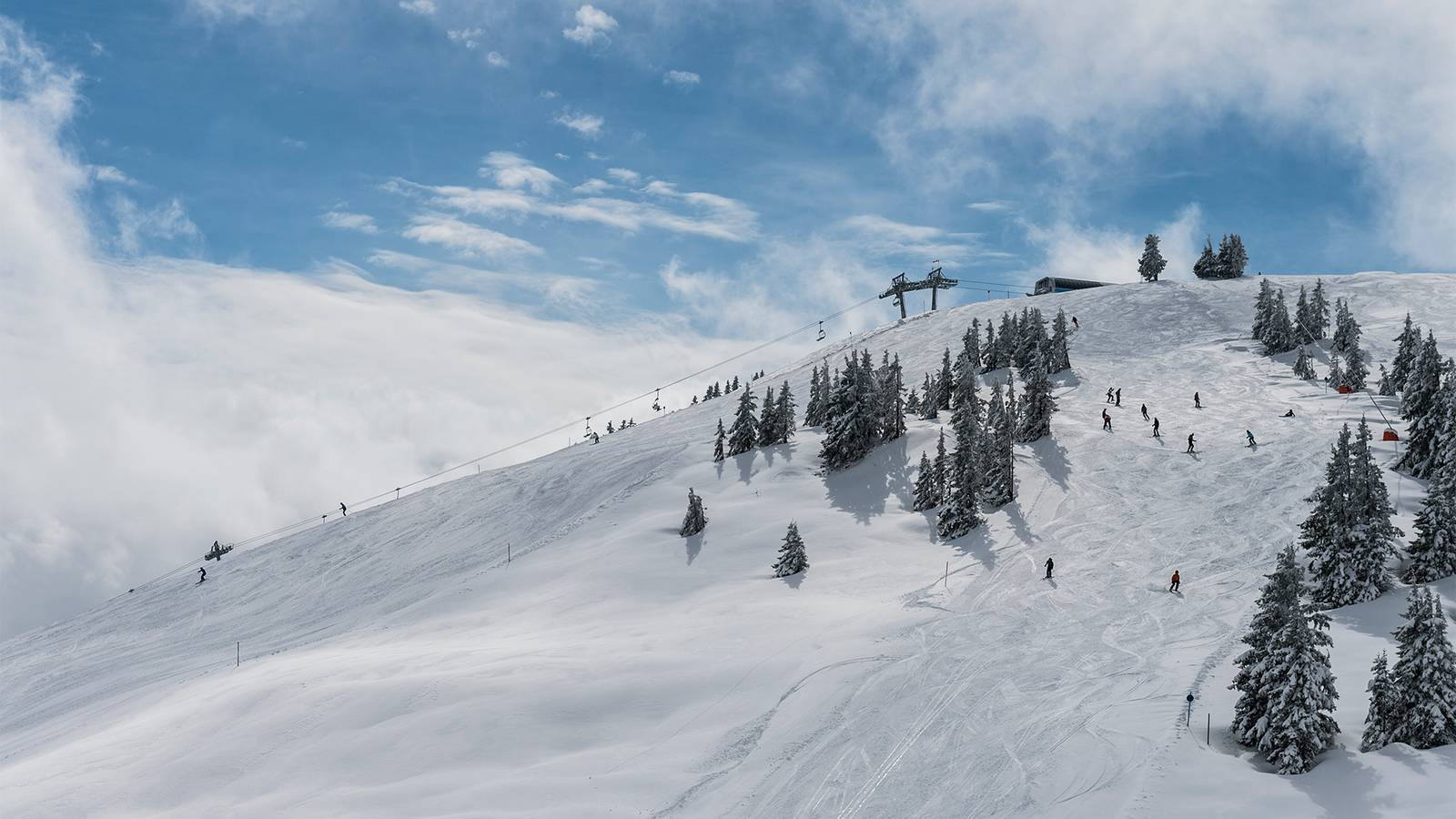 Aufnahme eines Berges mit Skipiste und Skifahrern.