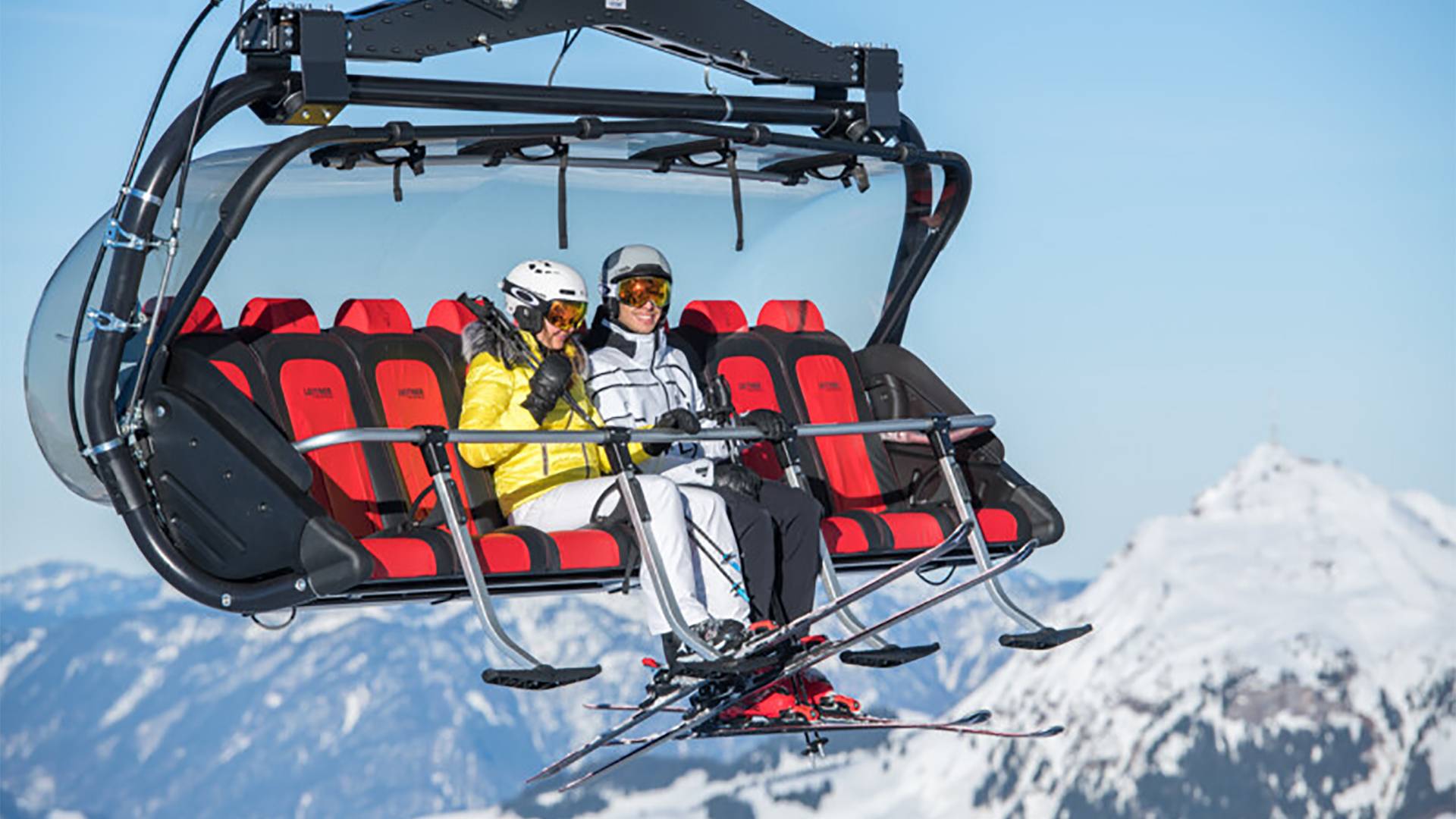 Zwei Personen sitzen in einem Sessellift in Kitzbühel.
