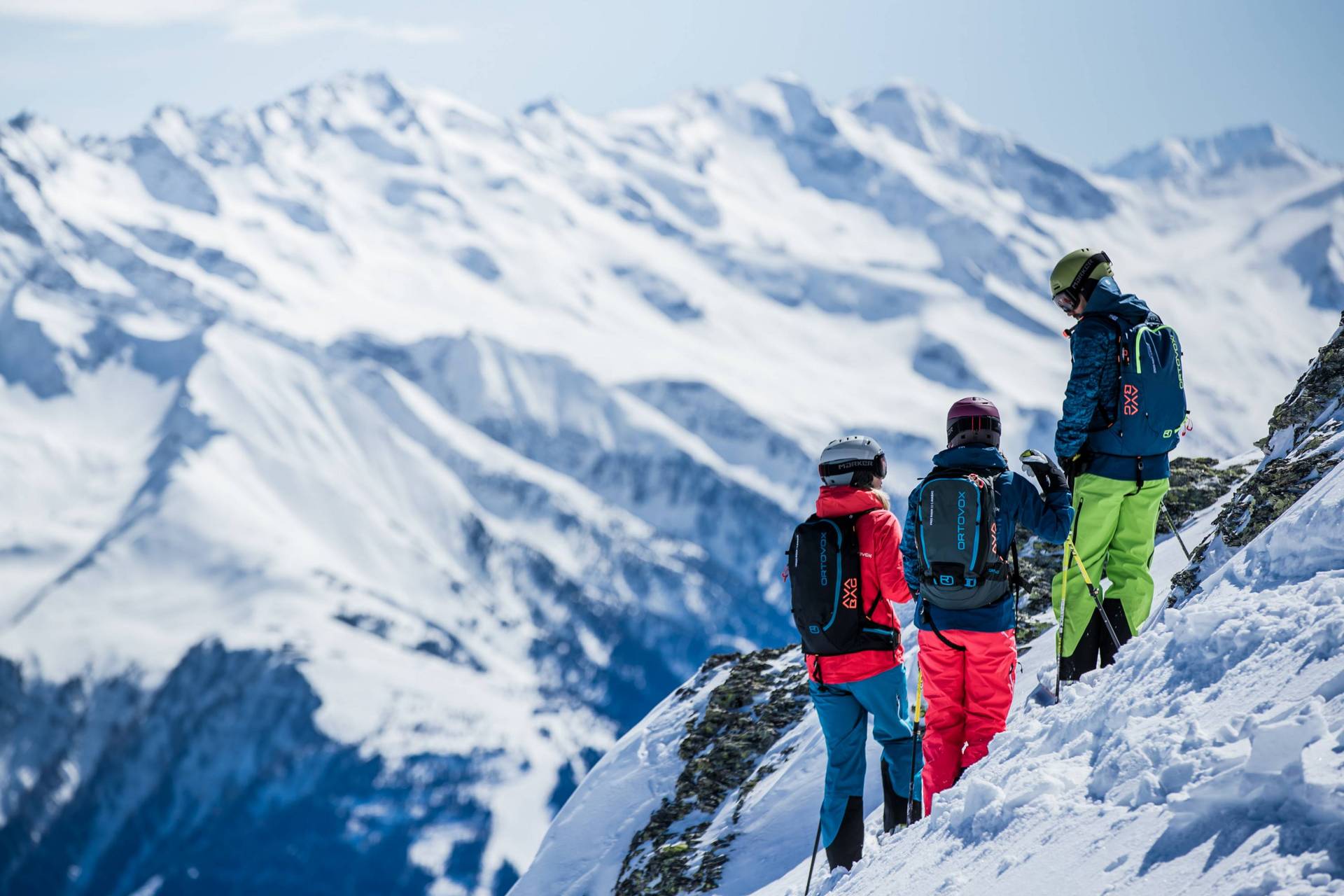 A beautiful mountain landscape with three people looking into the distance.