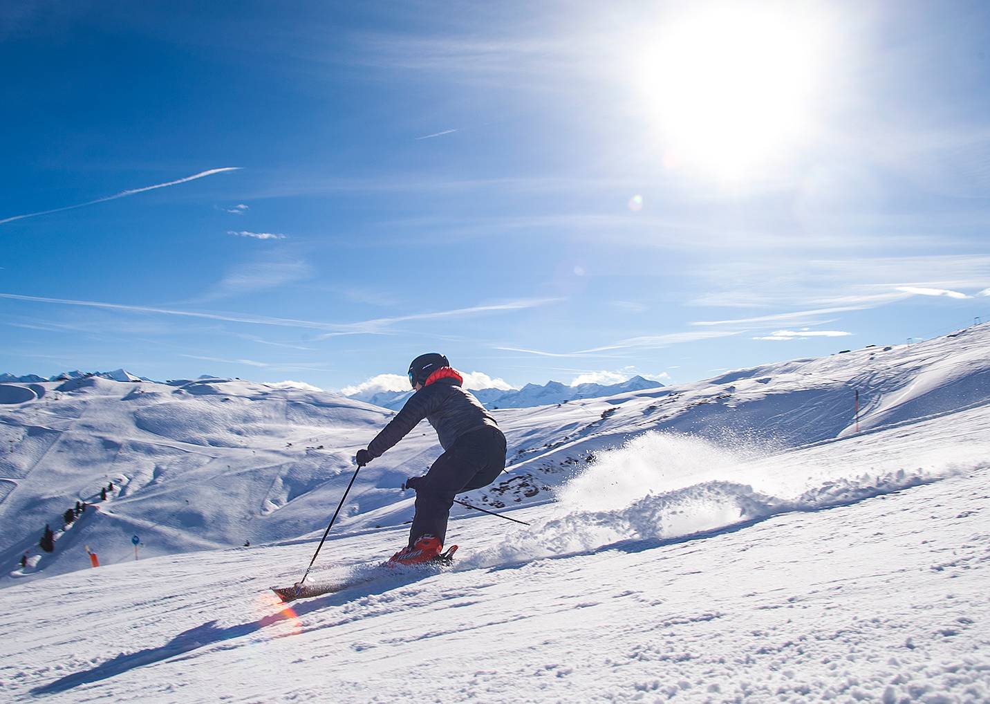 Ein Skifahrer fährt vor strahlend blauem Himmel die Piste hinunter.