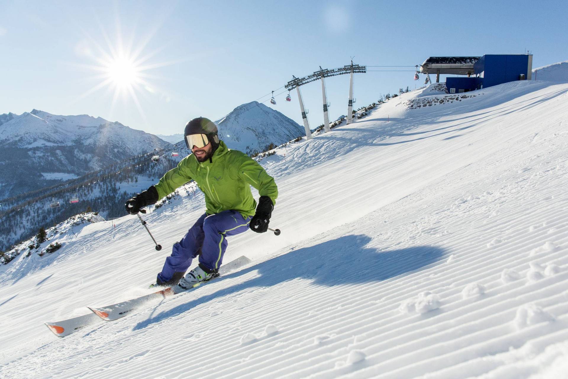 Een skiër met een groene jas skiet op een vers geprepareerde piste.