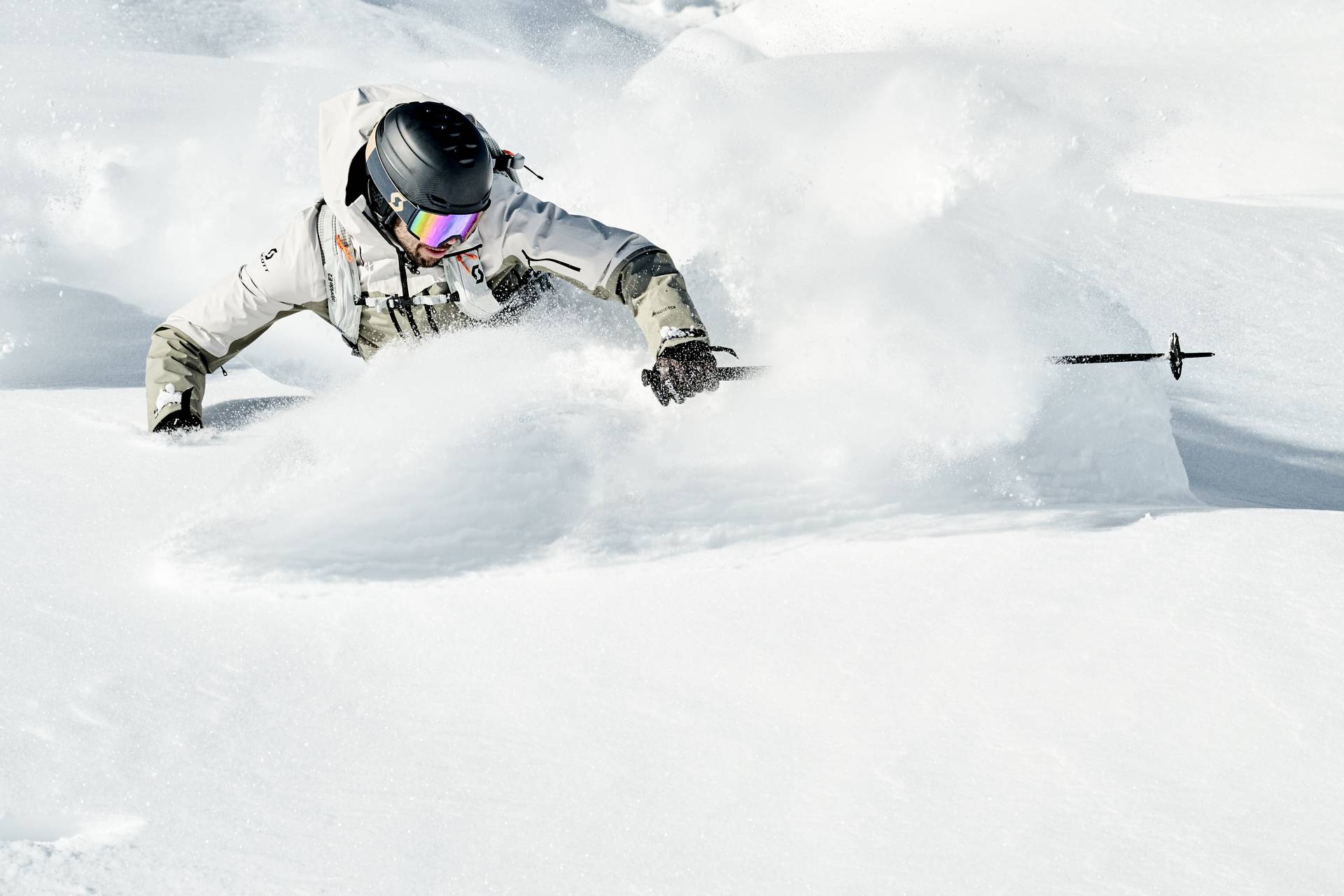 A skier is skiing in deep snow, his skis are deep in the snow, only his upper body is visible.