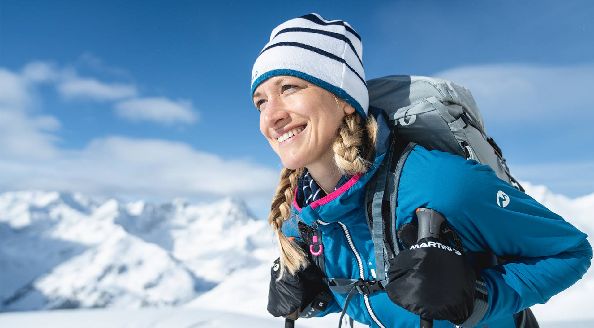 A female ski tourer enjoys the sun on the mountain.