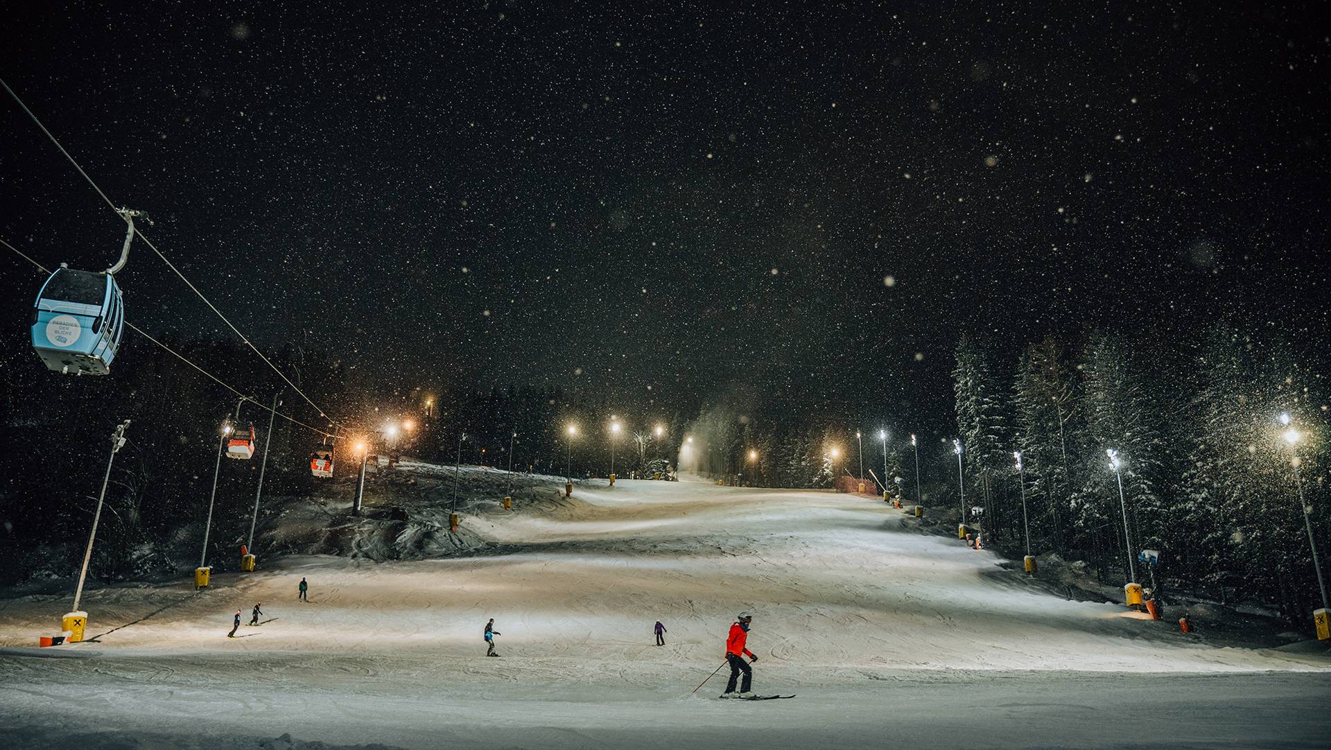 Skiers are skiing at night.