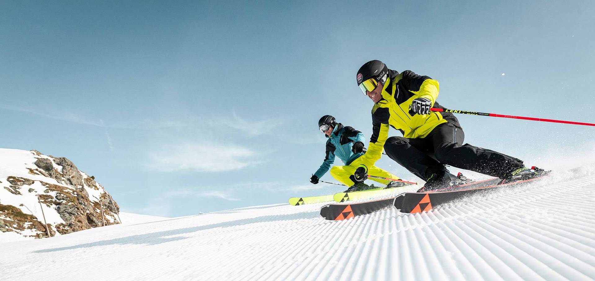 Zwei sportliche Skifahrer auf steiler Piste.