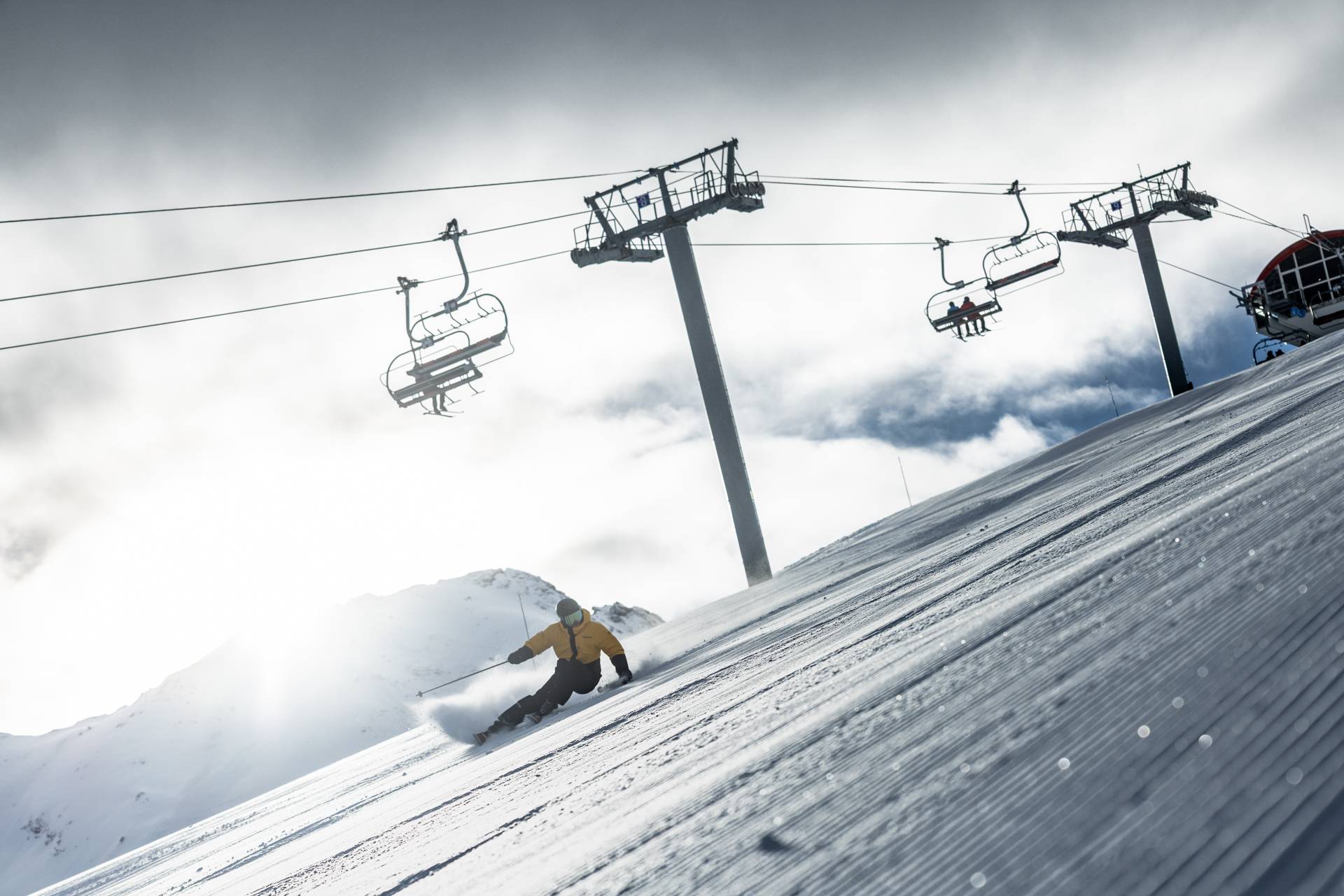 Skiër carvt over de piste, op de achtergrond zie je de stoeltjeslift.