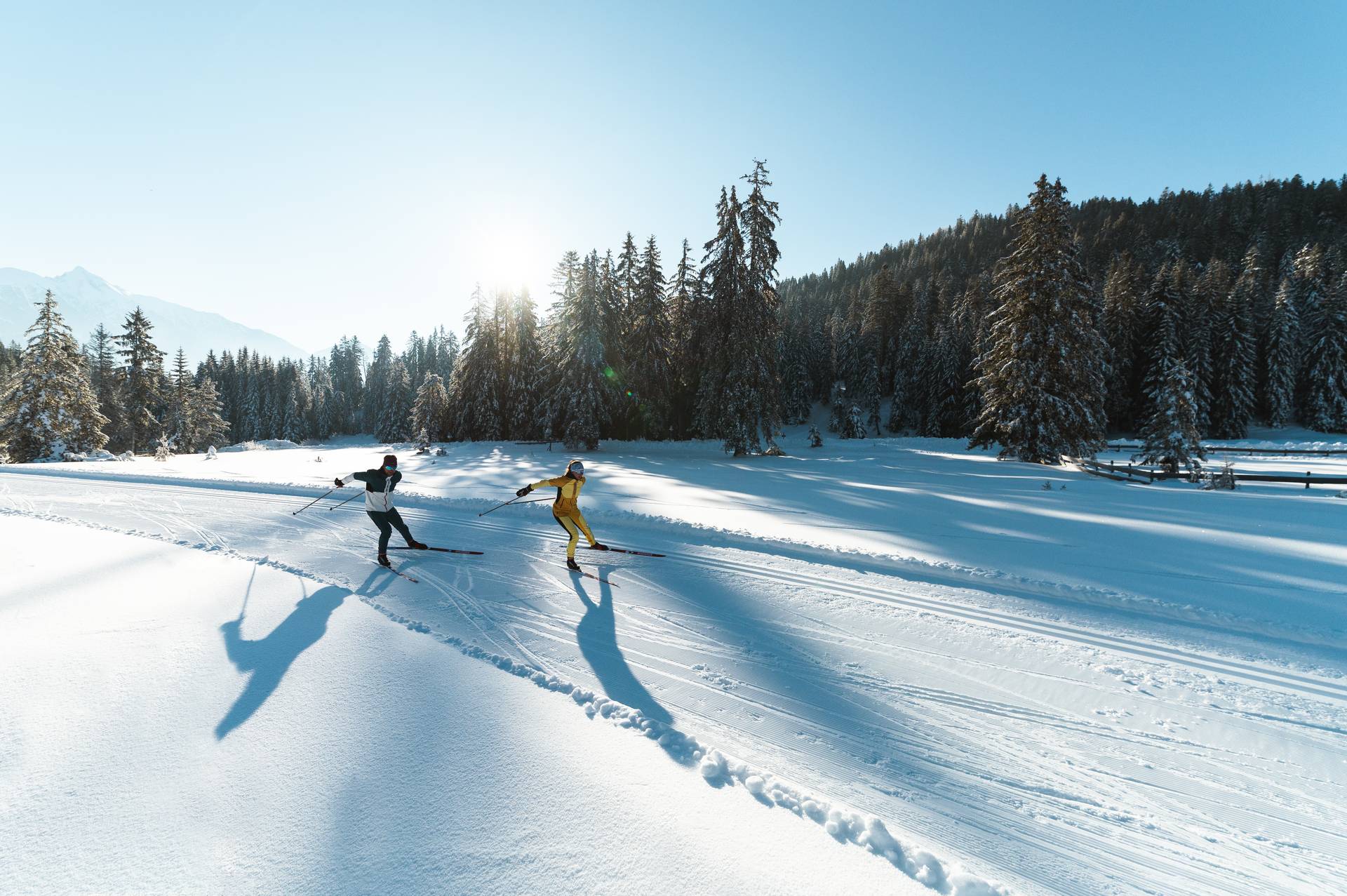 images-blog-langlaufen-lernen-2 Zwei Langläufer sind auf der Loipe unterwegs, die Sonne scheint