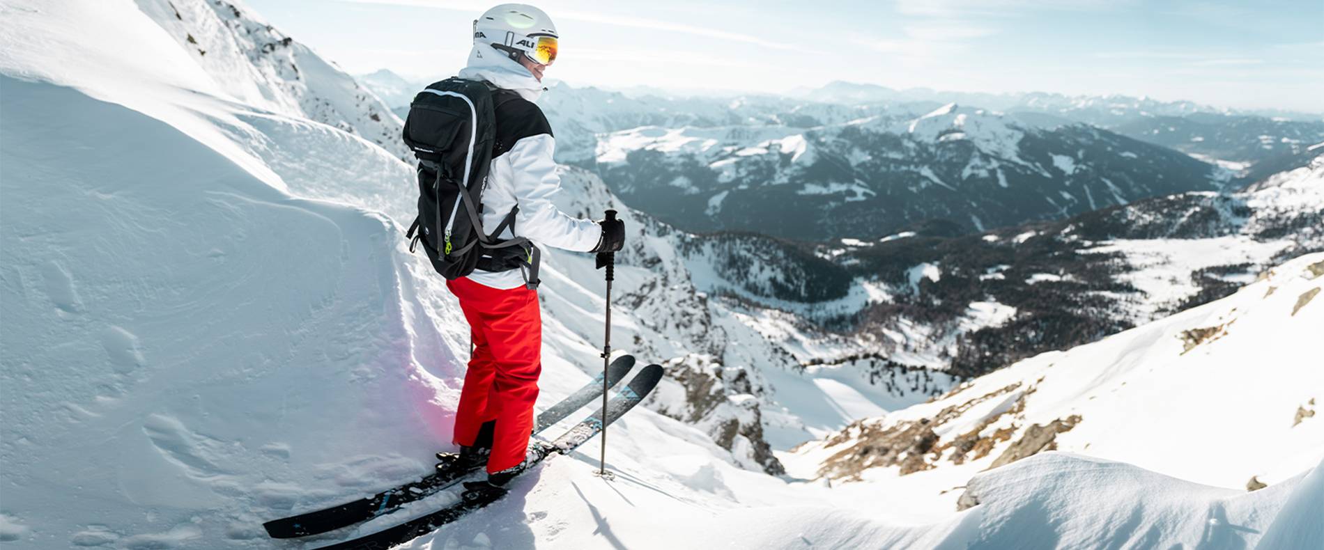 Hier steht eine Skifahrerin vor einer Freeride Abfahrt.