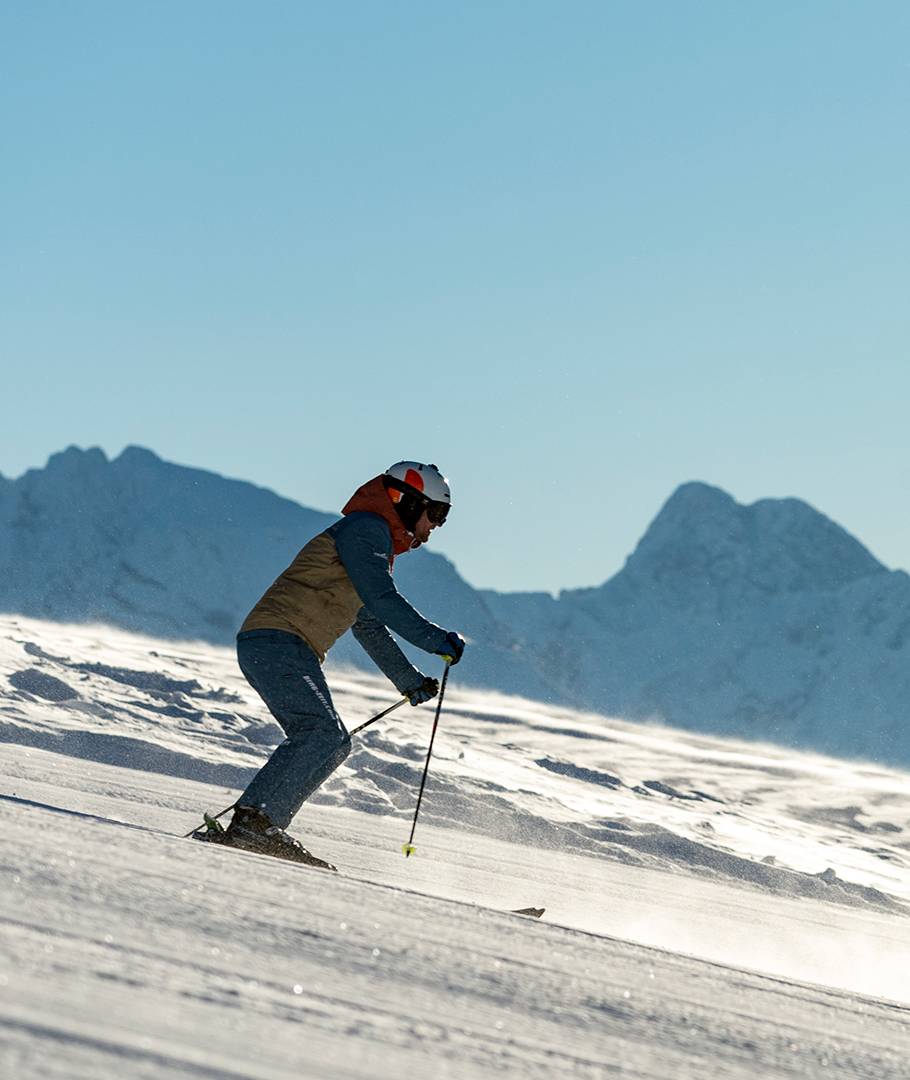 Ein Skifahrer ist bei strahlend blauem Himmel auf dem Weg ins Tal.