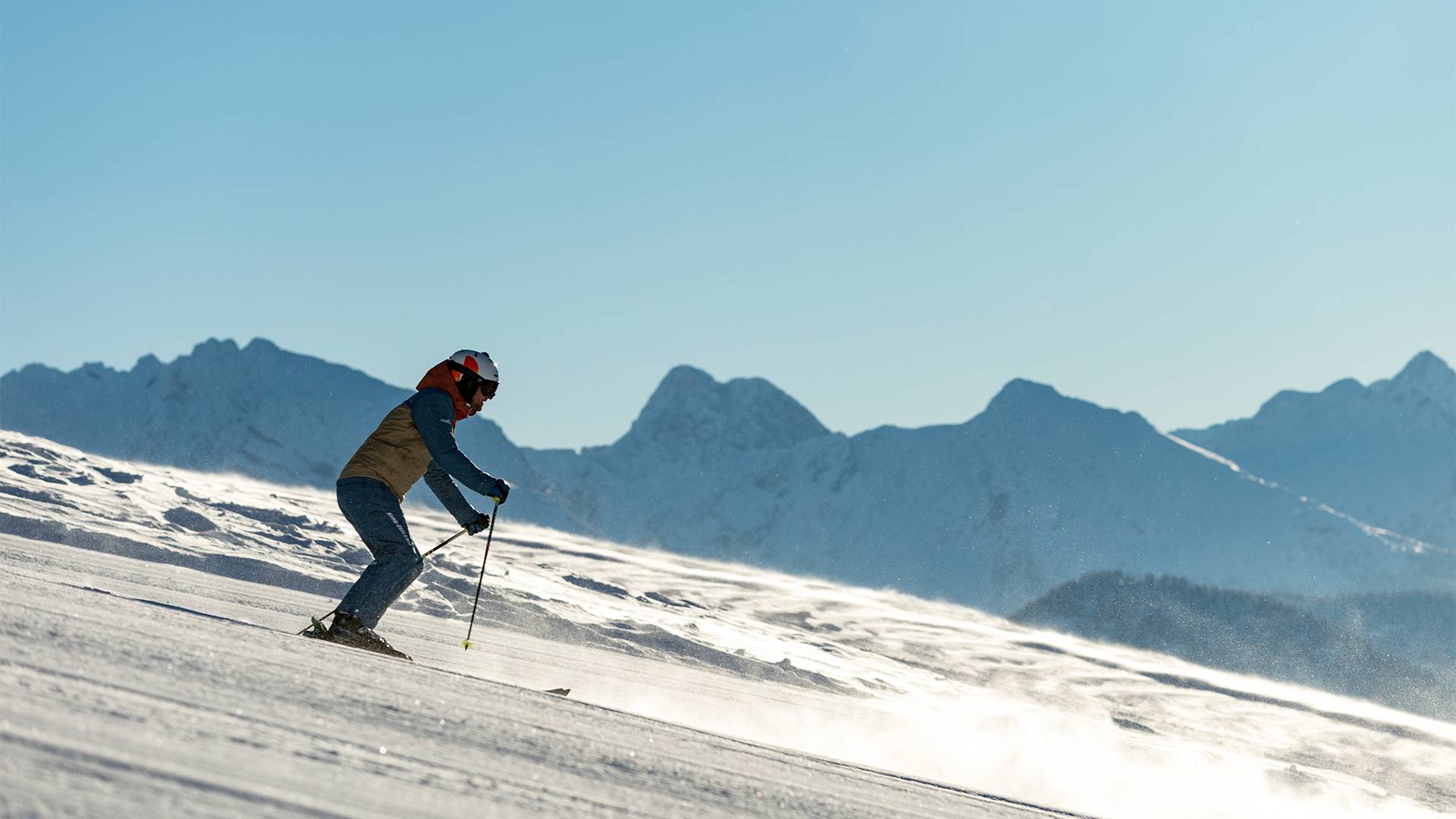 Een skiër is onder een stralend blauwe hemel op weg naar het dal.