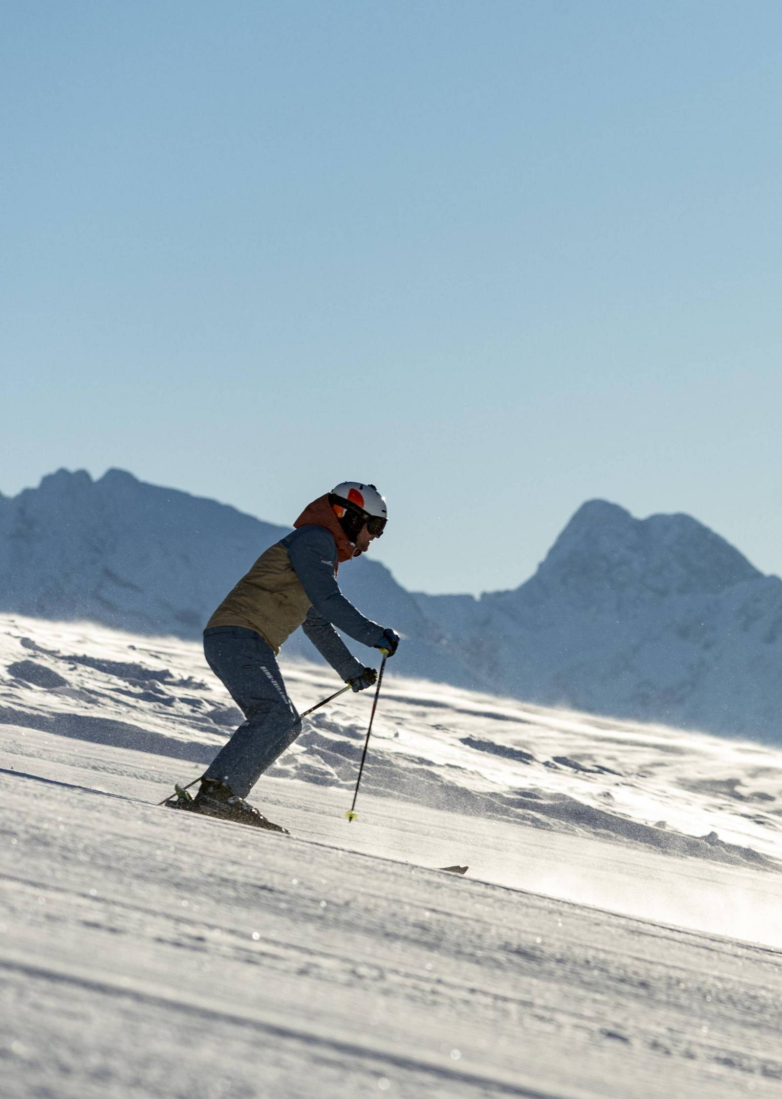 Ein Skifahrer ist bei strahlend blauem Himmel auf dem Weg ins Tal.