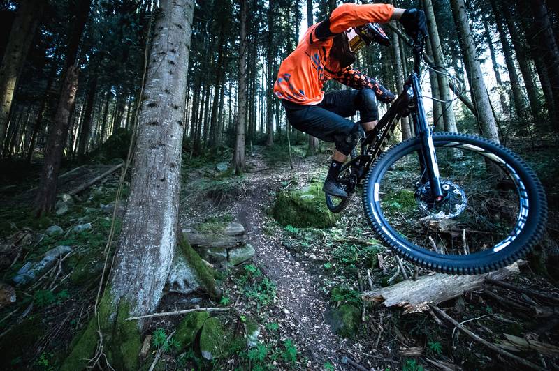 Biker festgehalten mitten im Sprung bergab auf einem Downhiltrail.