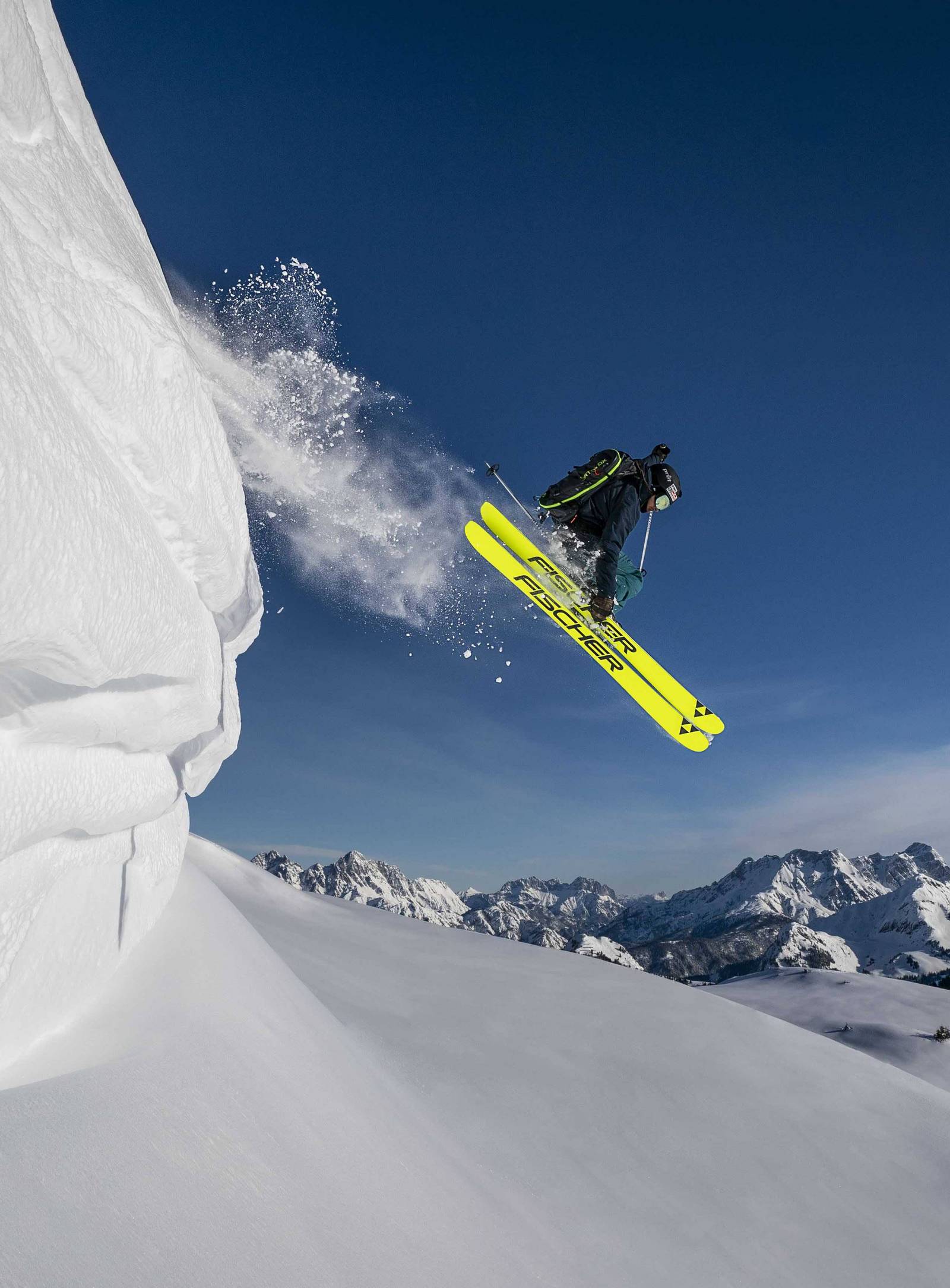 Ein Skifahrer springt über eine Neuschnee Schanze.