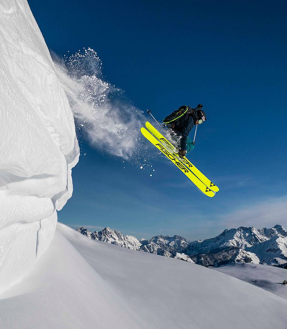 Ein Skifahrer springt über eine Neuschnee Schanze.