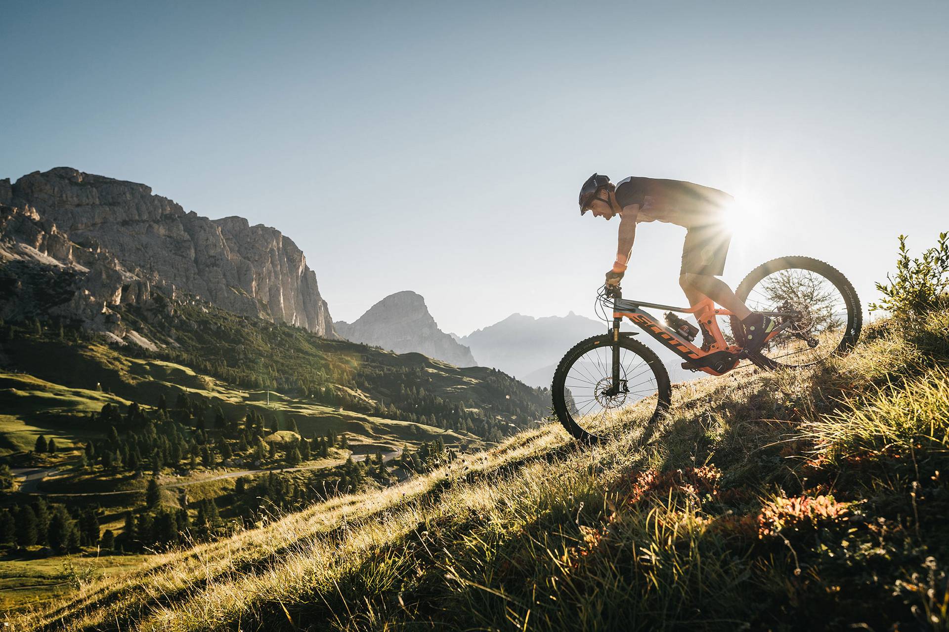 Ein Mountainbiker der bei frühabendlicher Stimmung in den Bergen unterwegs ist.