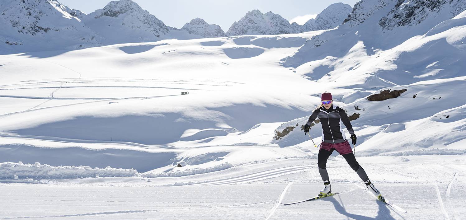 Eine Langläuferin ist in einer winterlicher Landschaft im Skatingstil unterwegs.