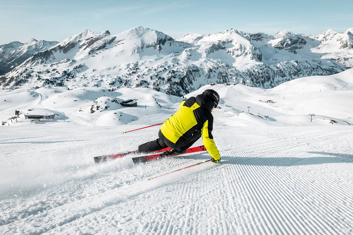 Ein Skifahrer carvt über die Piste.