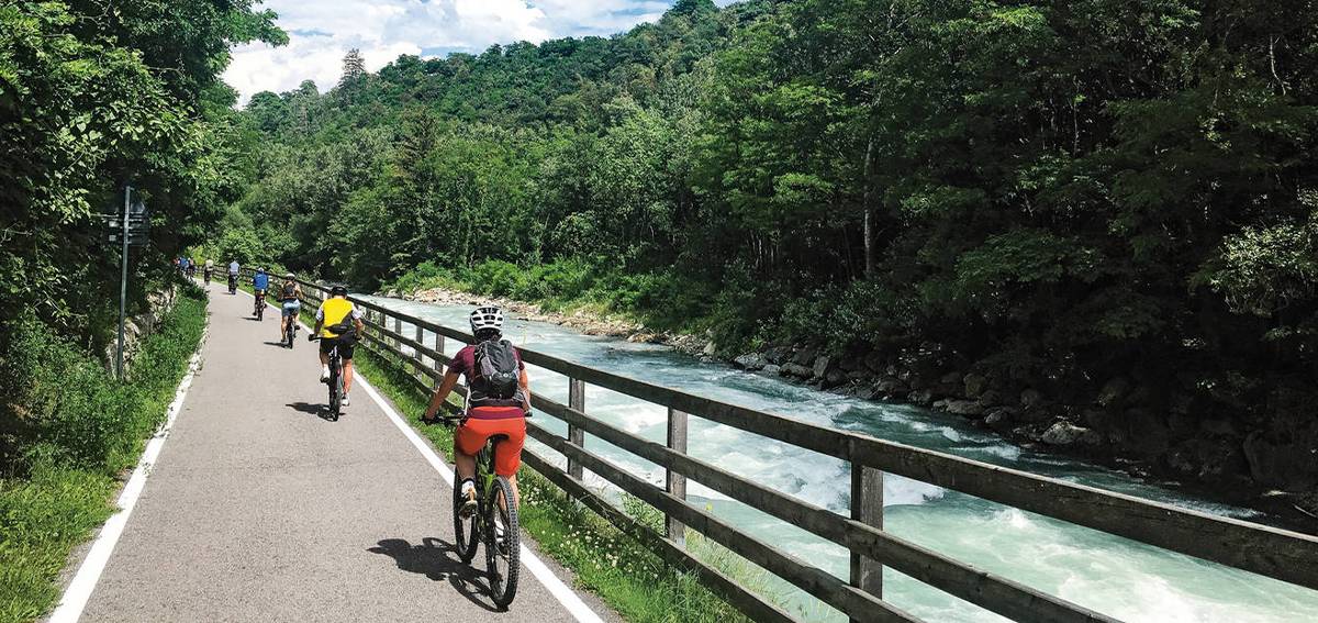 Eine Gruppe von Radfahrern die in Südtirol neben einem Fluss fahren.