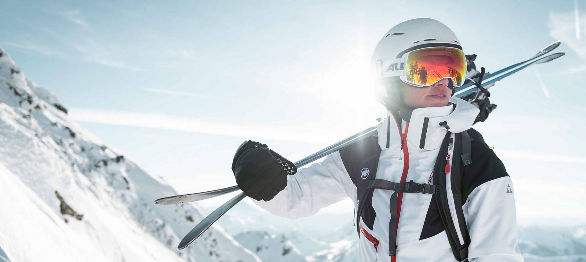 A skier carries her skis over her shoulder.