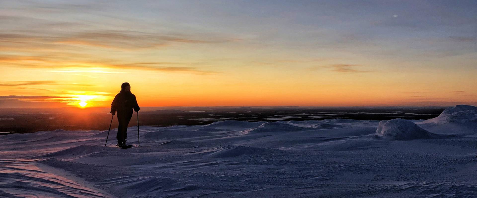 Hij kijkt tijdens het toerskiën naar de zonsondergang.