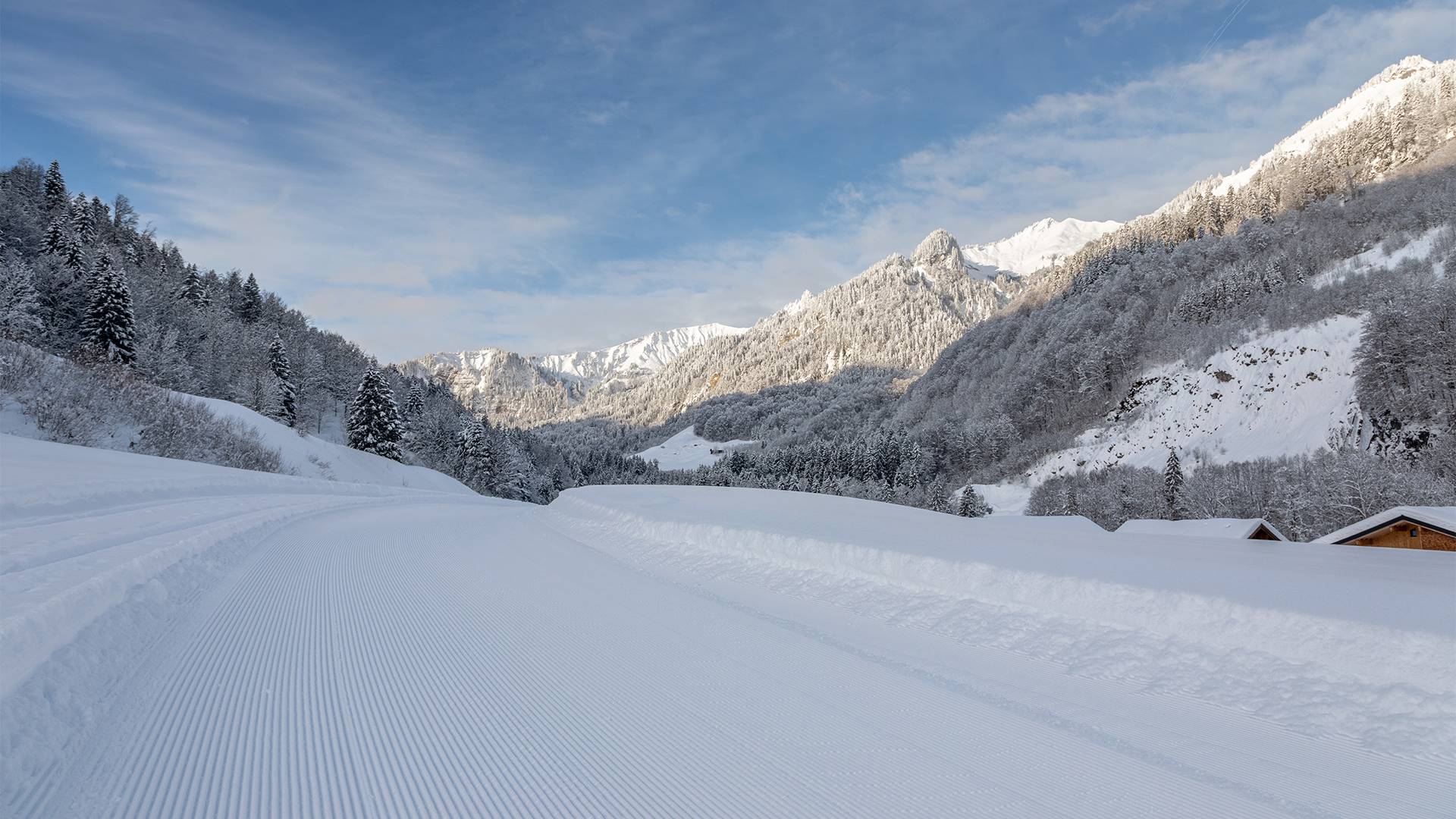 Een langlaufloipe die links en rechts omgeven is door heuvels.