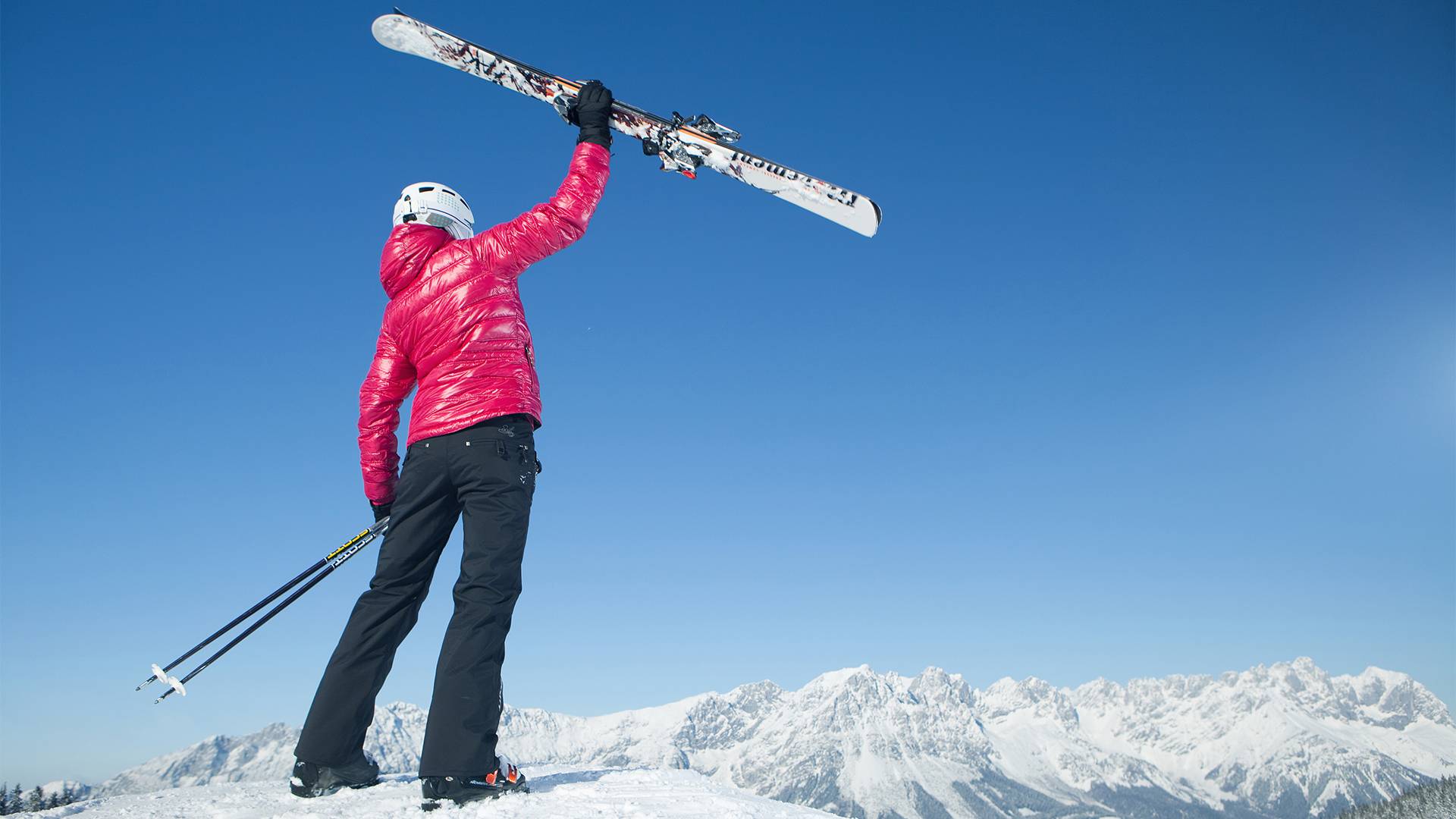 Photo of a woman holding up her skis.