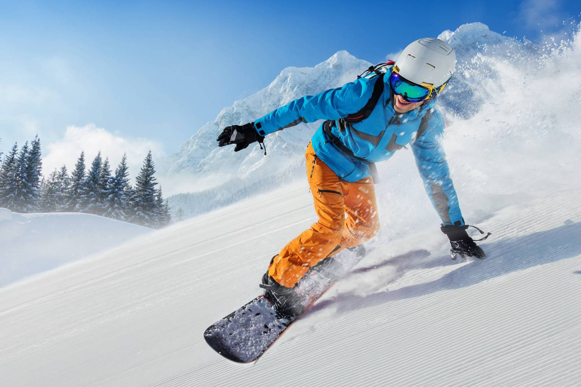 Ein ambitionierter Snowboarder fährt die Piste runter. Im Hintergrund sind Wald und Berge zu sehen.