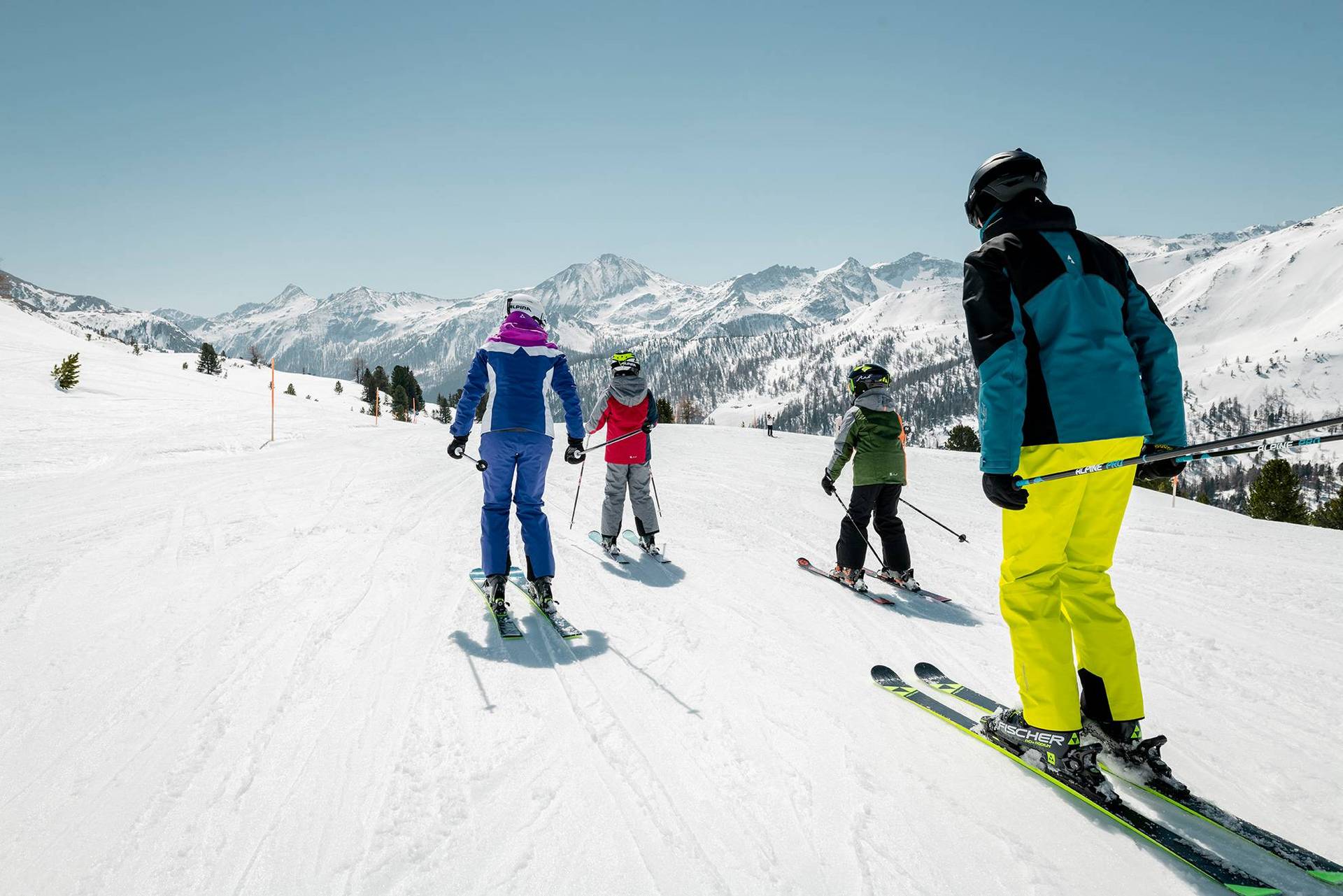 Ouders en kinderen skiën samen op een gemakkelijke skipiste.