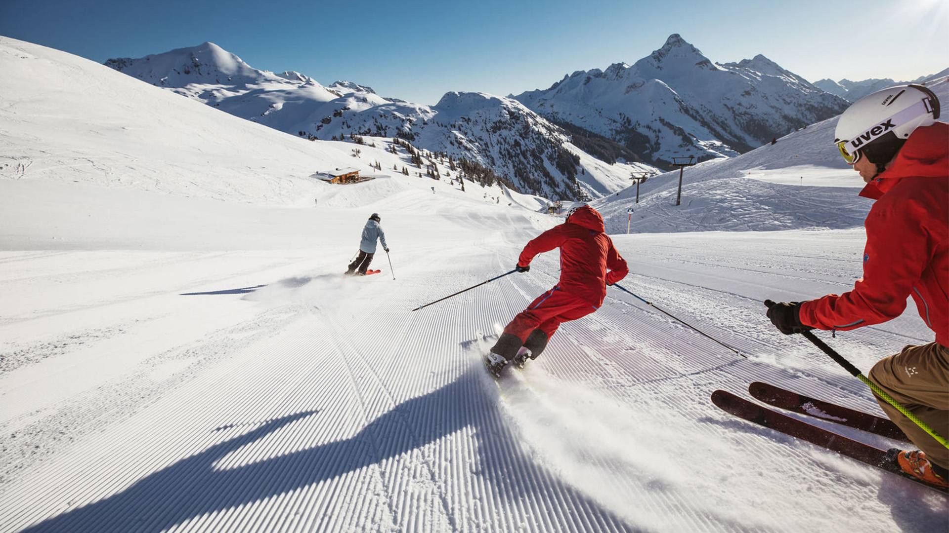 Skifahrer fahren eine gut präparierte Piste hinunter.