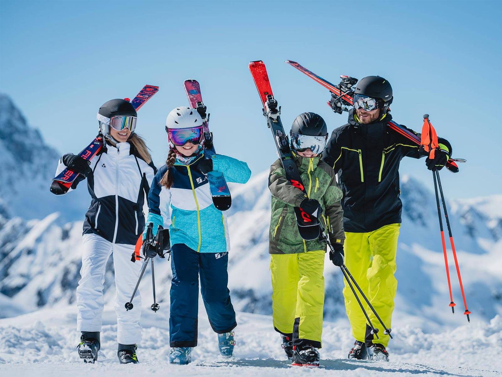 Eine Familie steht in Skiausrüstung nebeneinander und wird von unten fotografiert.