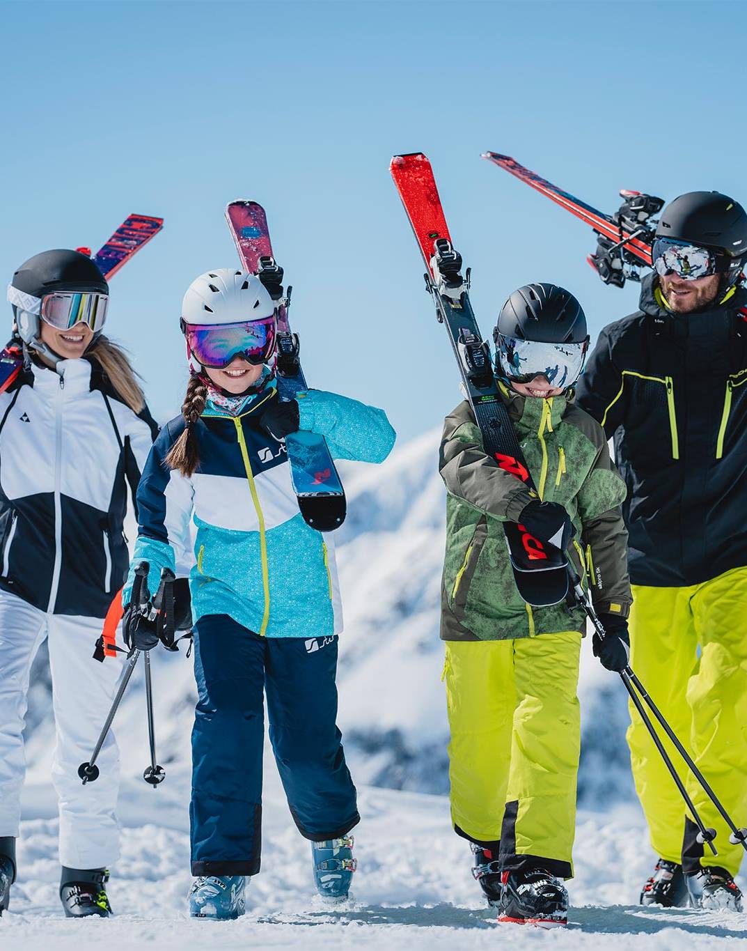 Eine Familie steht in Skiausrüstung nebeneinander und wird von unten fotografiert.