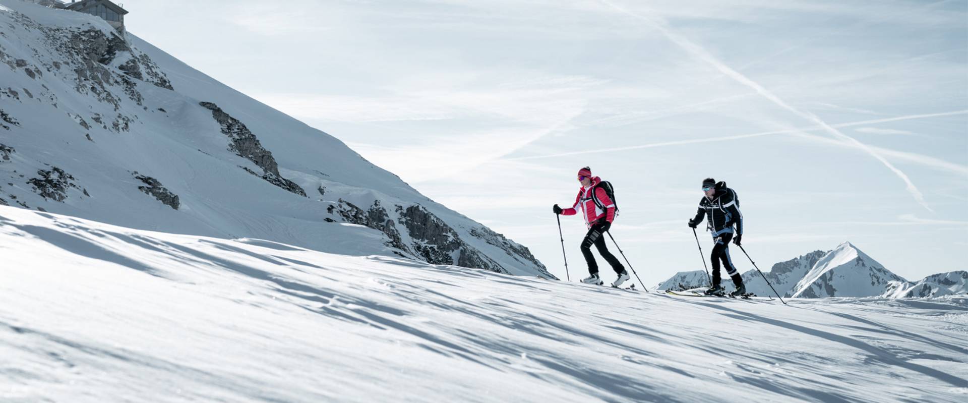 Two cross-country skiers skiing down the slope.