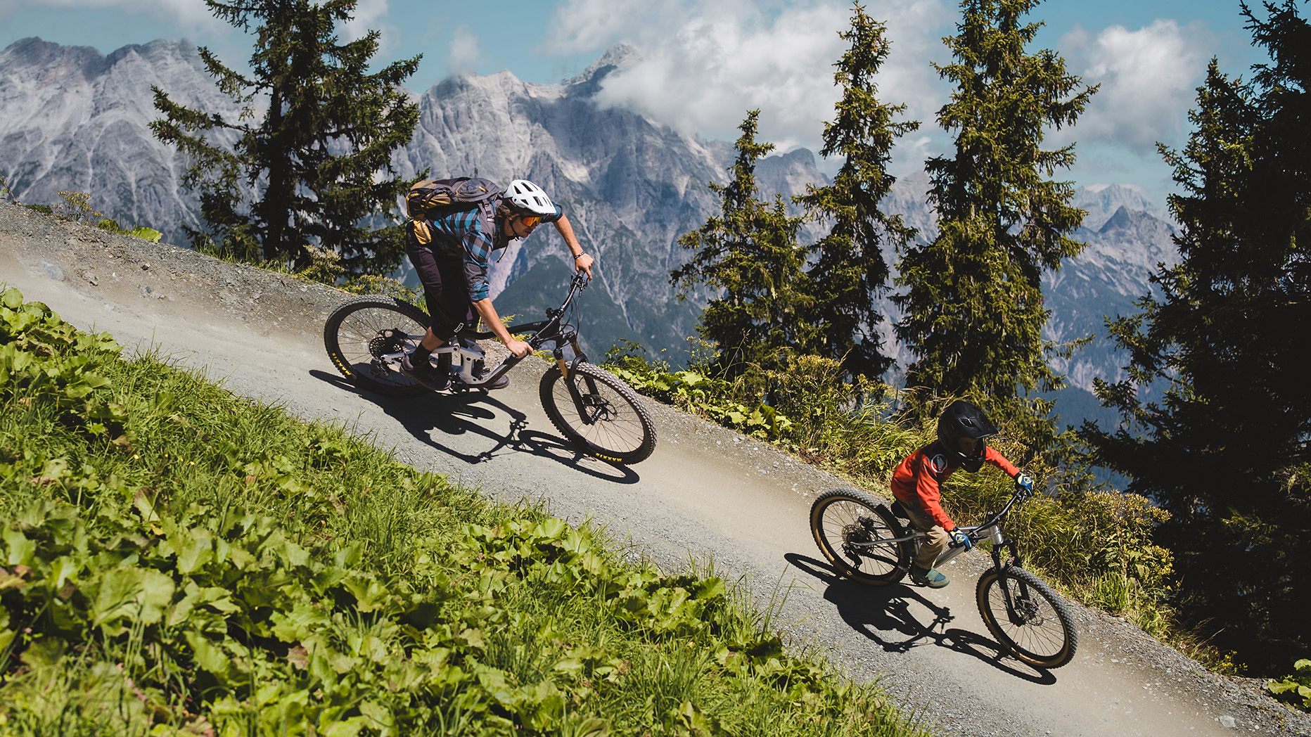 Eine Familie am E-Bike mit Kindern im Radanhänger, genießt die herrliche Radstrecke durch die Berglandschaft.