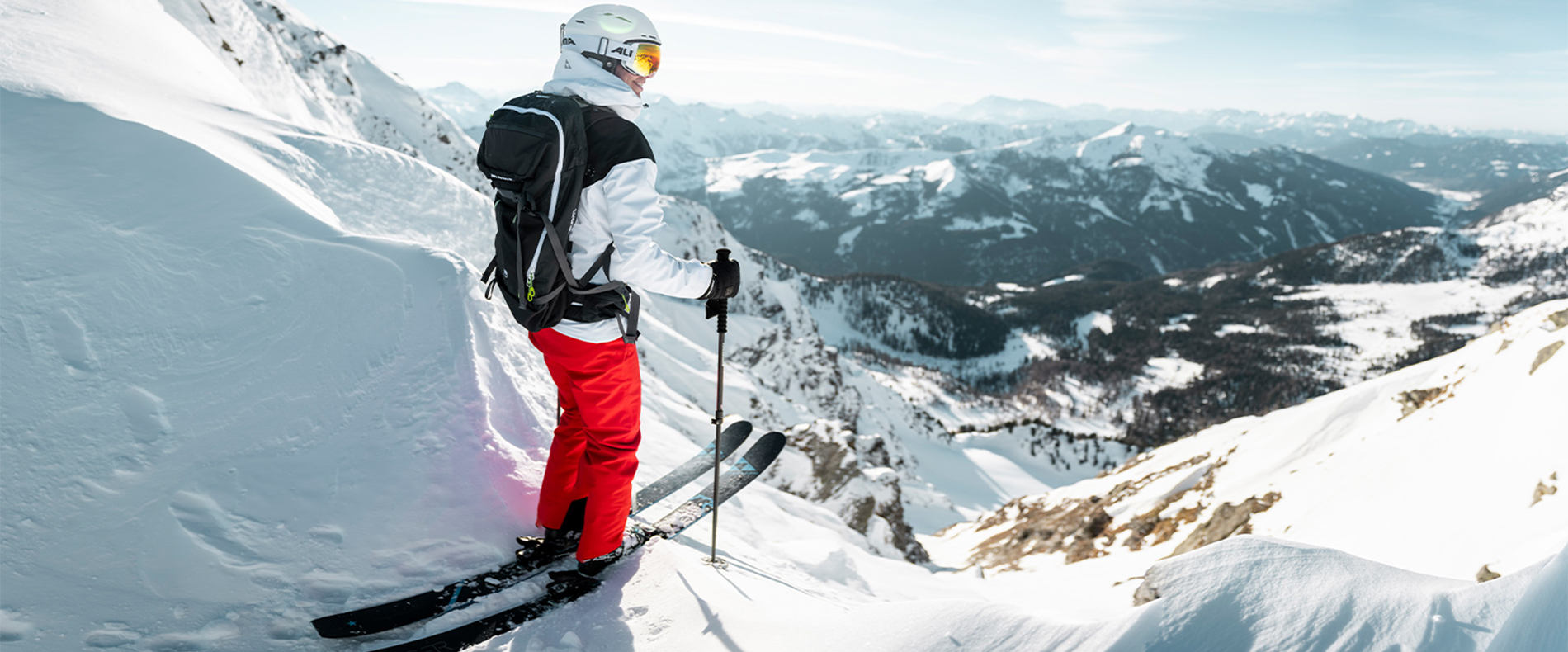 Hier steht eine Skifahrerin vor einer Freeride Abfahrt. 