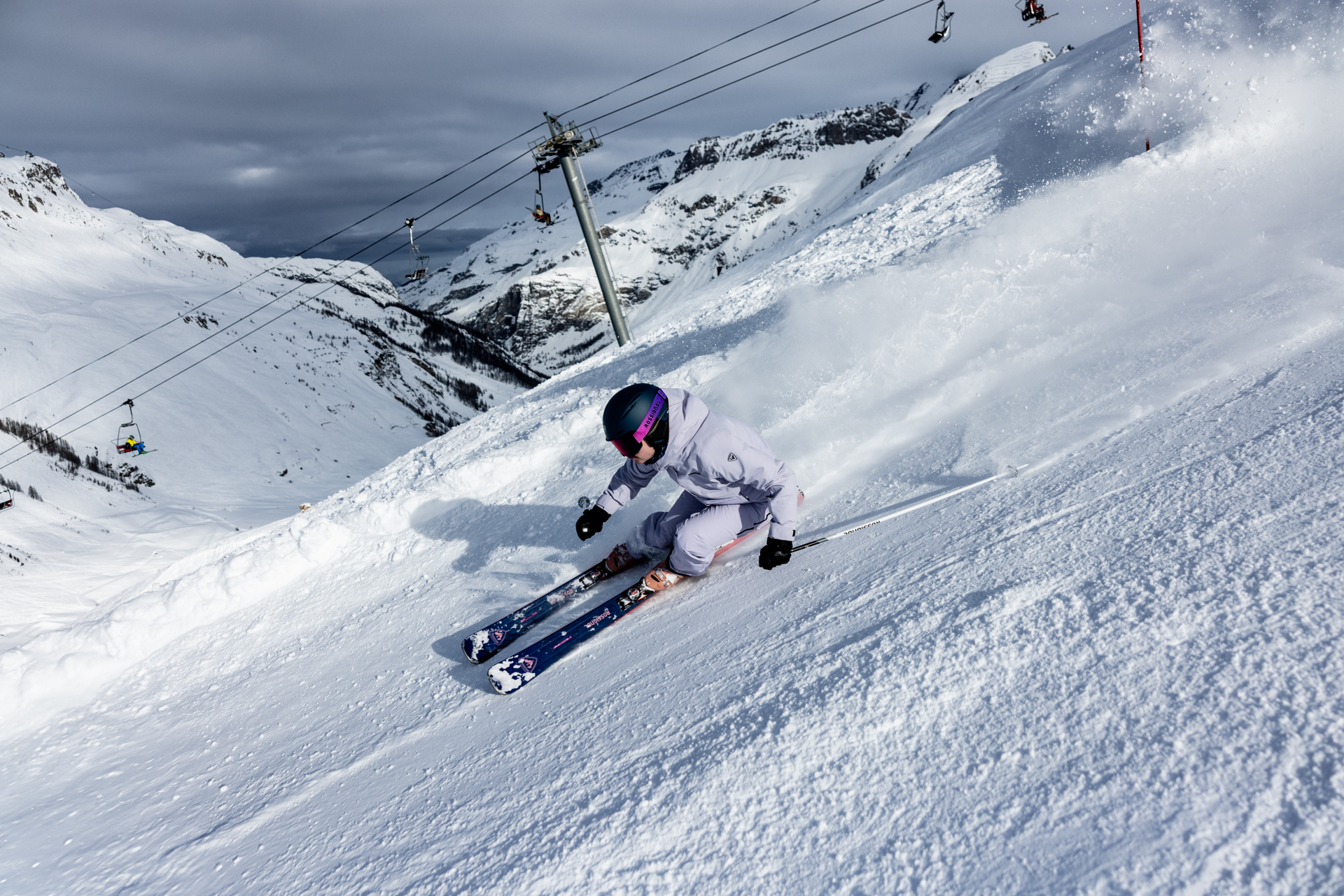 Skifahrerin fährt auf der Piste, der Sessellift ist im Hintergrund zu sehen