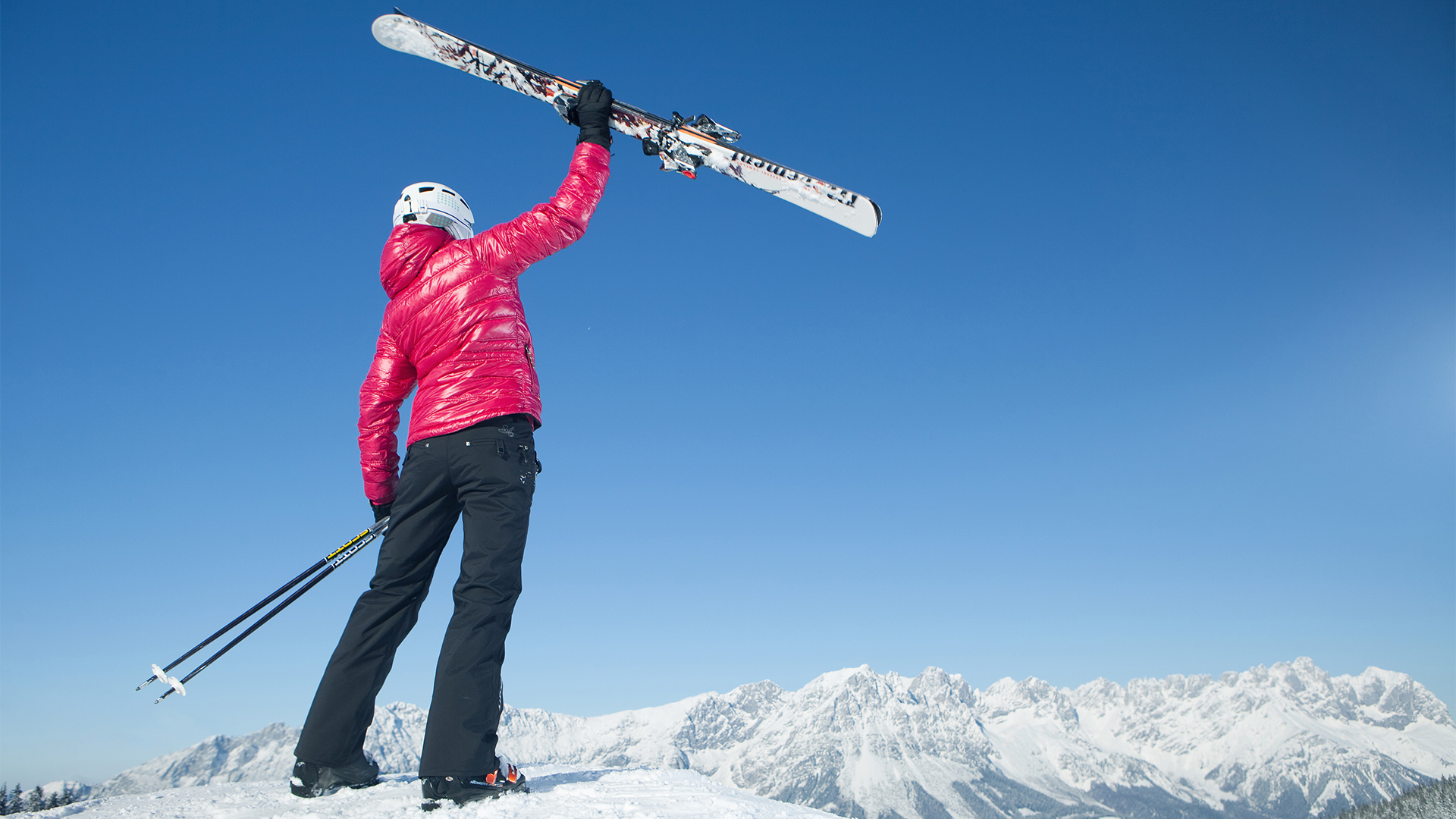 Foto von einer frau, welche die Ski in die Höhe hält.