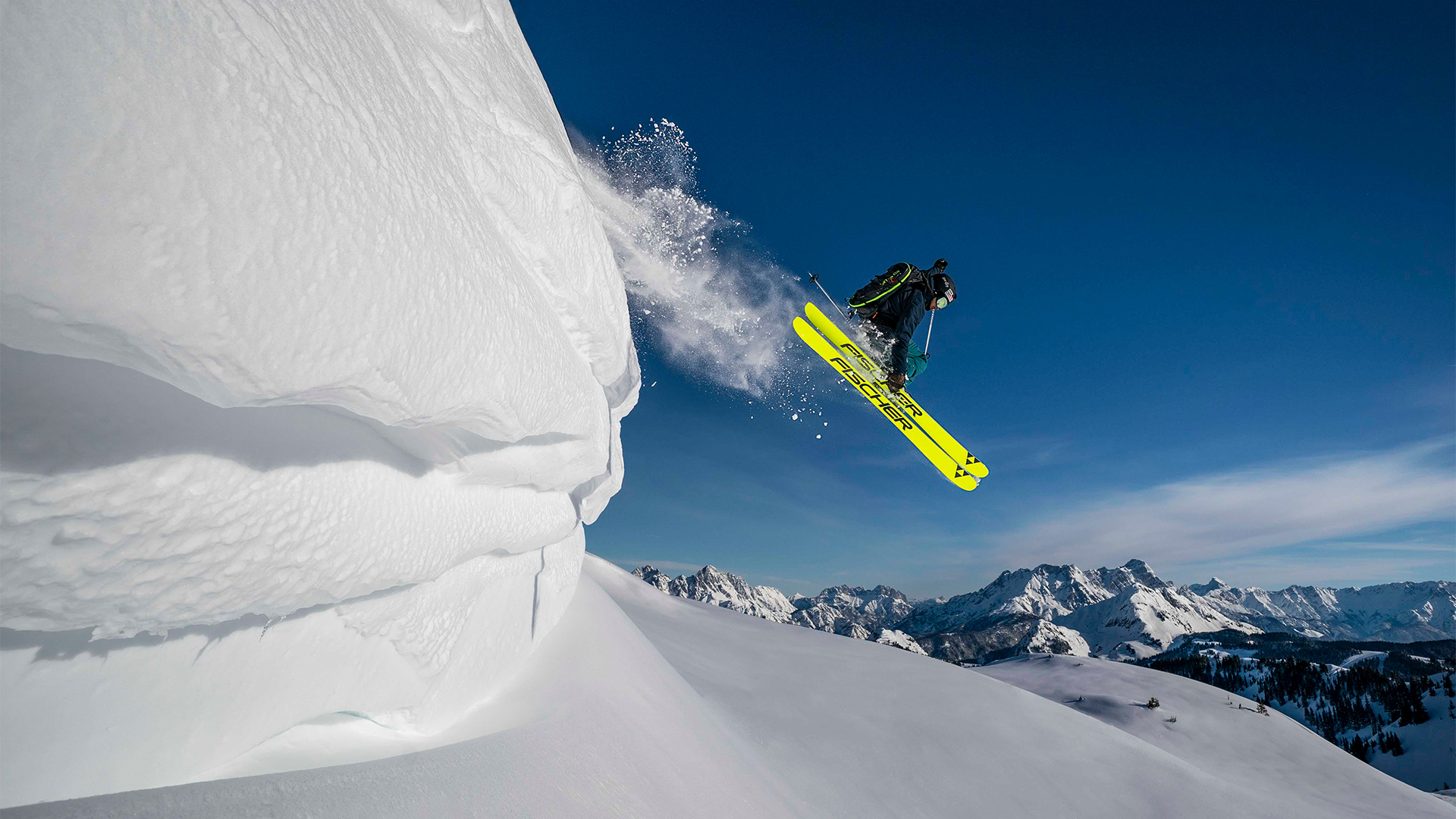 Ein Skifahrer springt über eine Neuschnee Schanze.