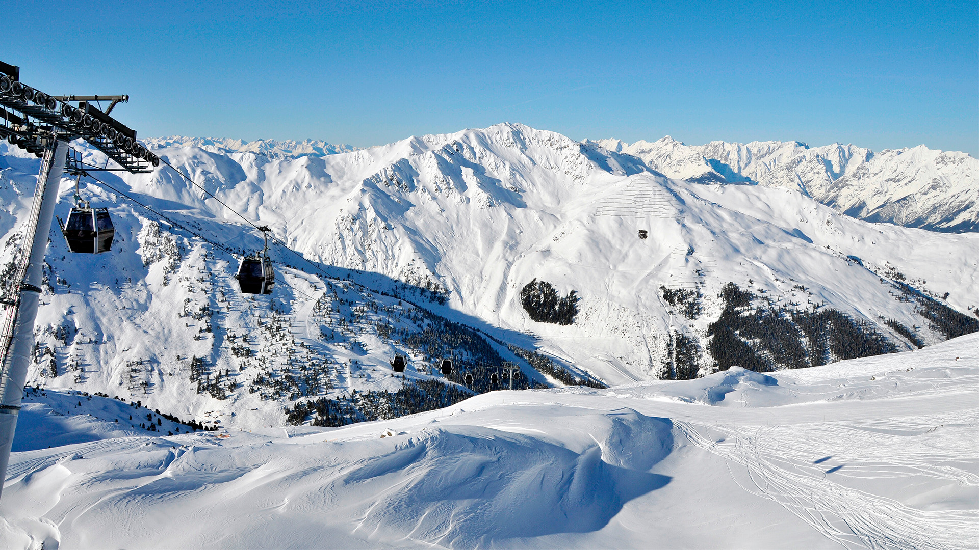 Die Gondeln der Bahn Zillertal Shuttle fahren vor imposantem Bergpanorama.