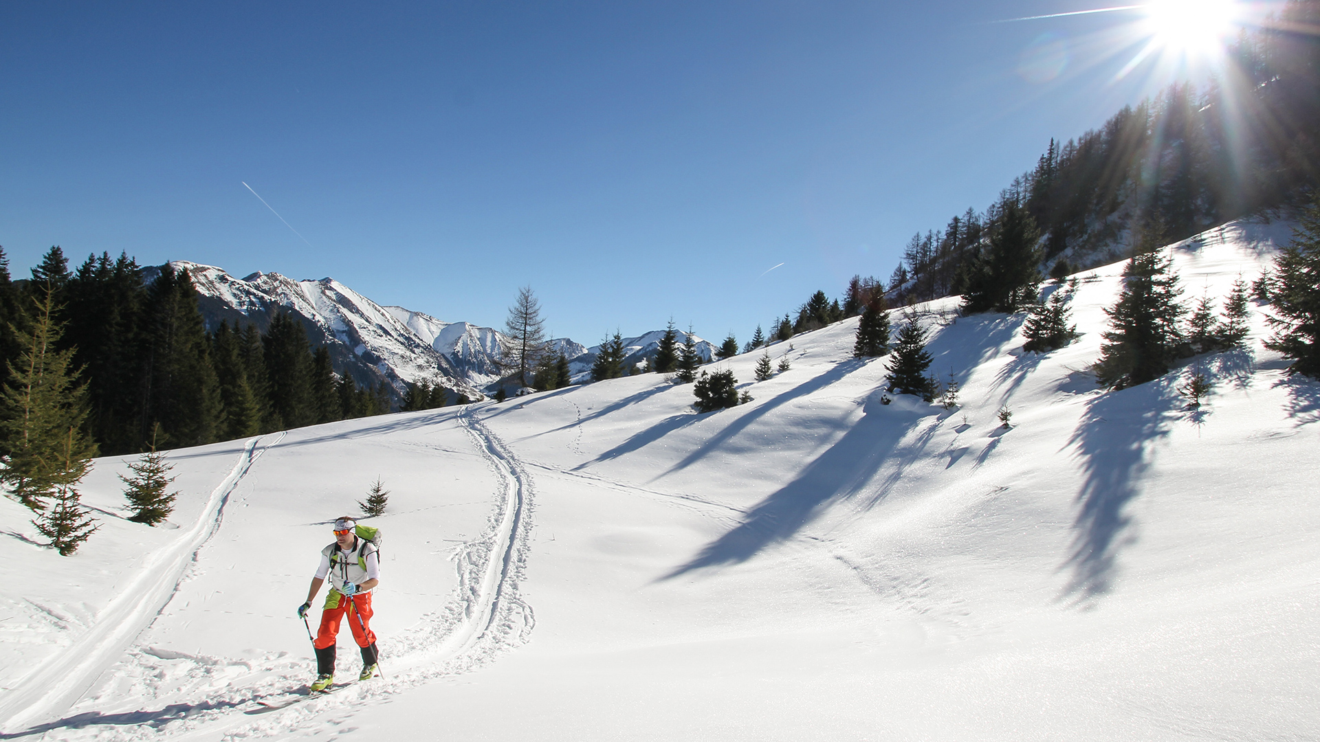 Ein Tourengeher ist ärmellos auf dem Weg zum Gipfel und genießt den Sonnenschein.