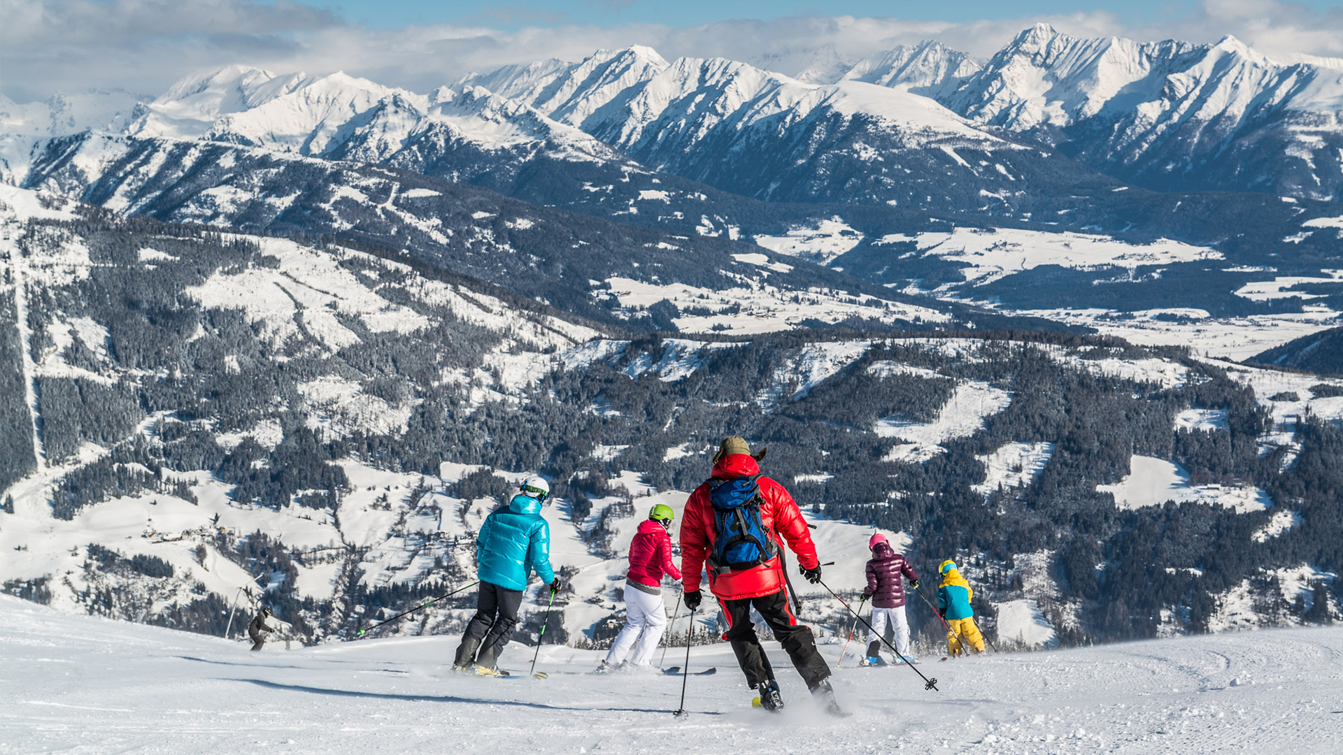 Eine Gruppe Skifahrer fährt eine Piste in Katschberg hinunter.