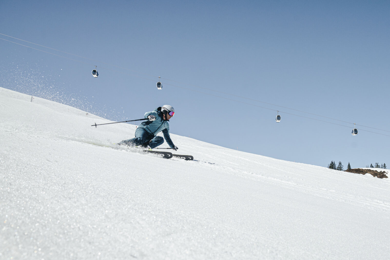 Skifahrerin f&auml;hrt auf der Skipiste, im Hintergrund ist die Gondelbahn zu sehen