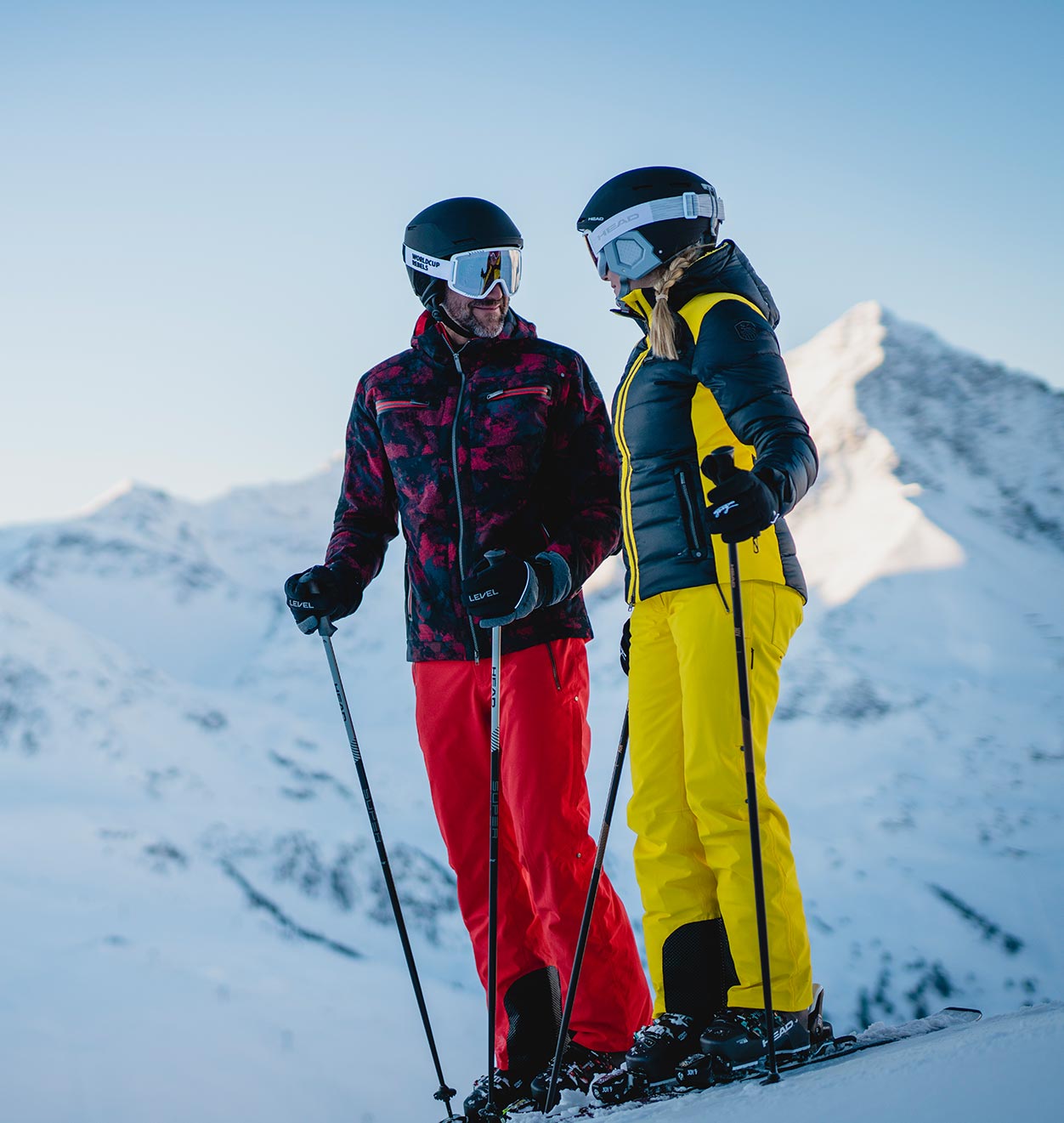 Eine Frau trägt ihre Ski, indem sie diese auf ihrer rechten Schulter stützt und sie dabei mit der rechten Hand festhält.