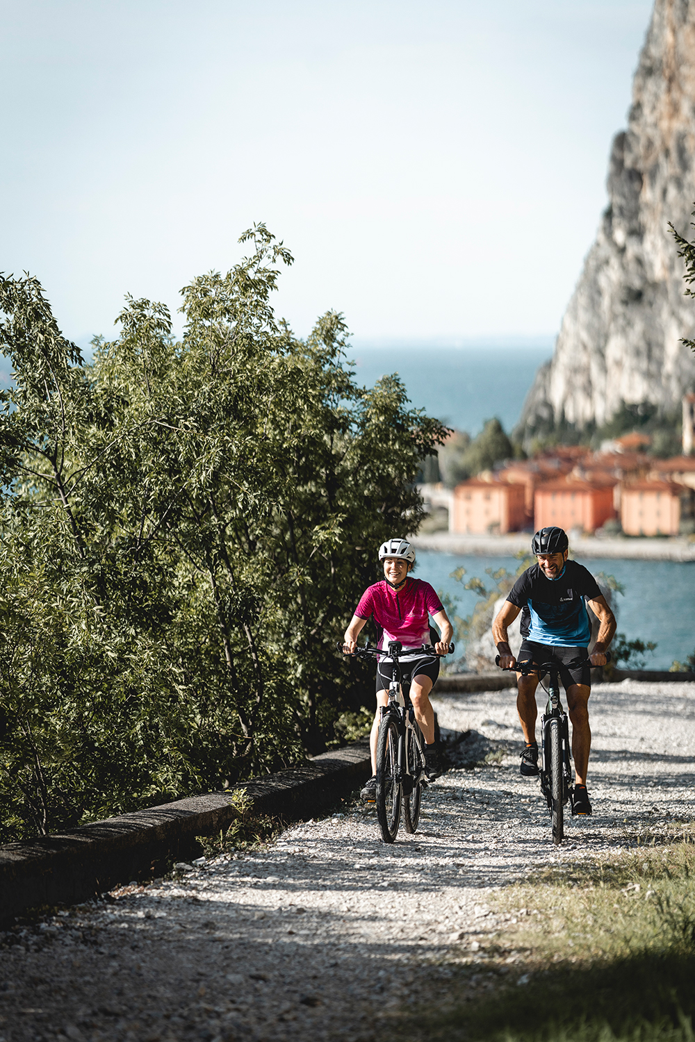 Zwei Radfahrer genießen ihren Tag und fahren auf einer Forststrraße neben einem See.